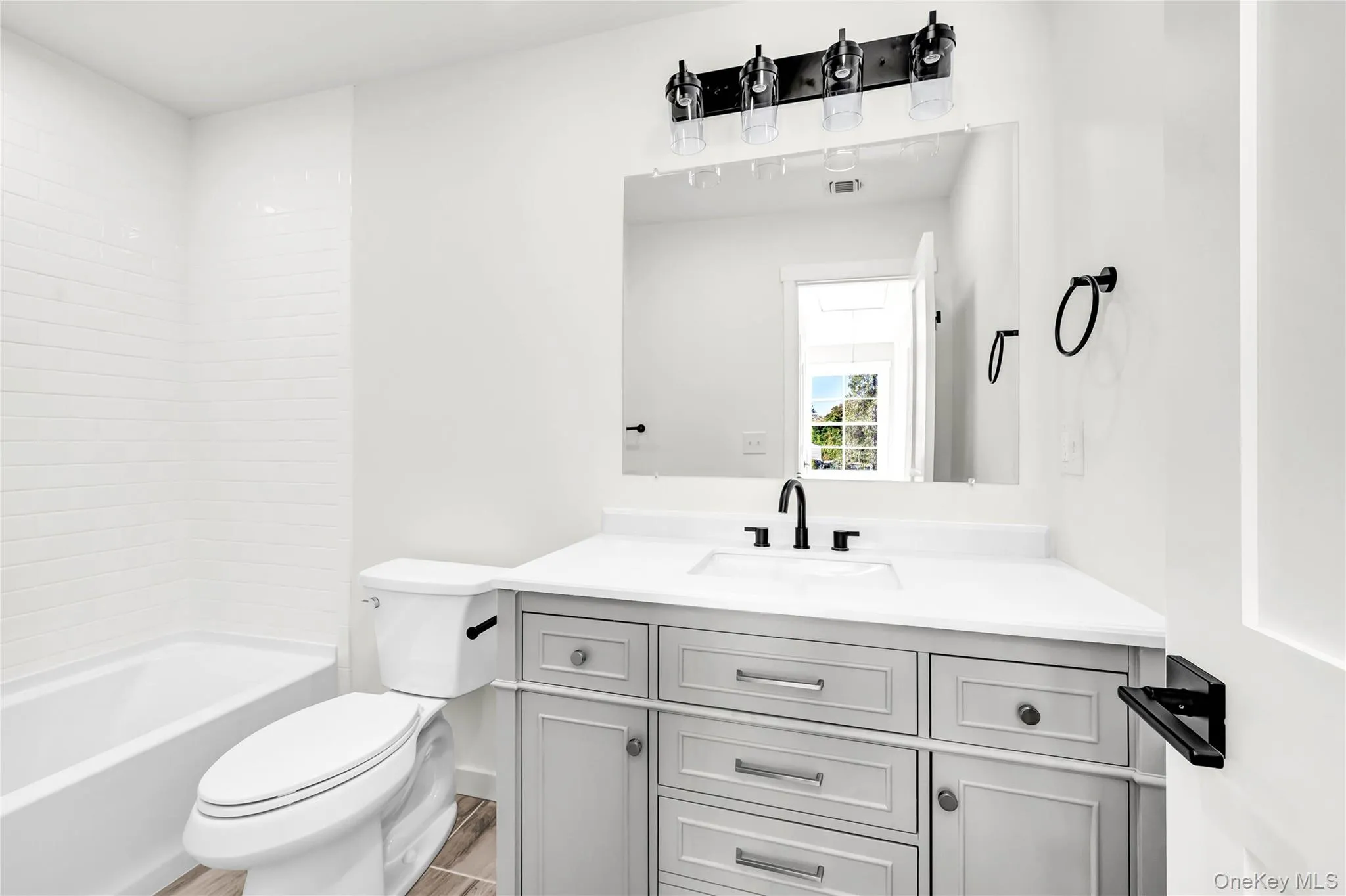 Bathroom featuring vanity, shower / tub combination, and wood finished floors Bathroom featuring vanity, shower / tub combination, and wood finished floors