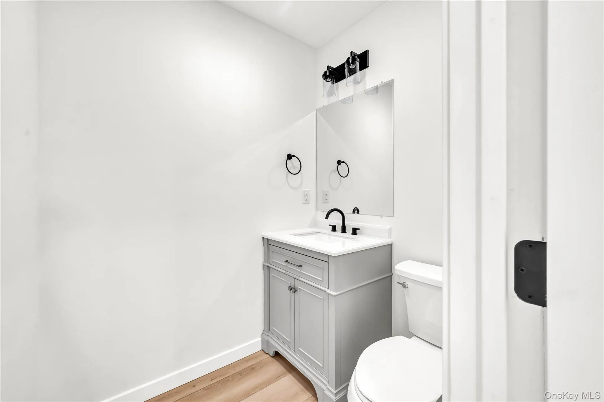 Half bathroom featuring vanity and light wood-style floors Half bathroom featuring vanity and light wood-style floors