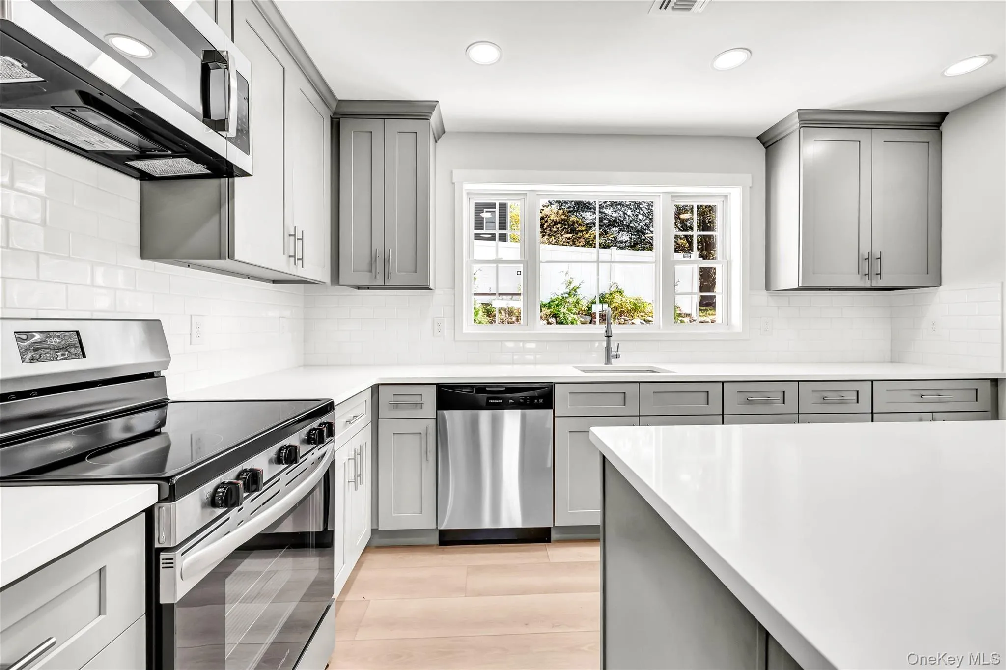 Kitchen with gray cabinetry, stainless steel appliances, recessed lighting, and light wood-style floors Kitchen with gray cabinetry, stainless steel appliances, recessed lighting, and light wood-style floors