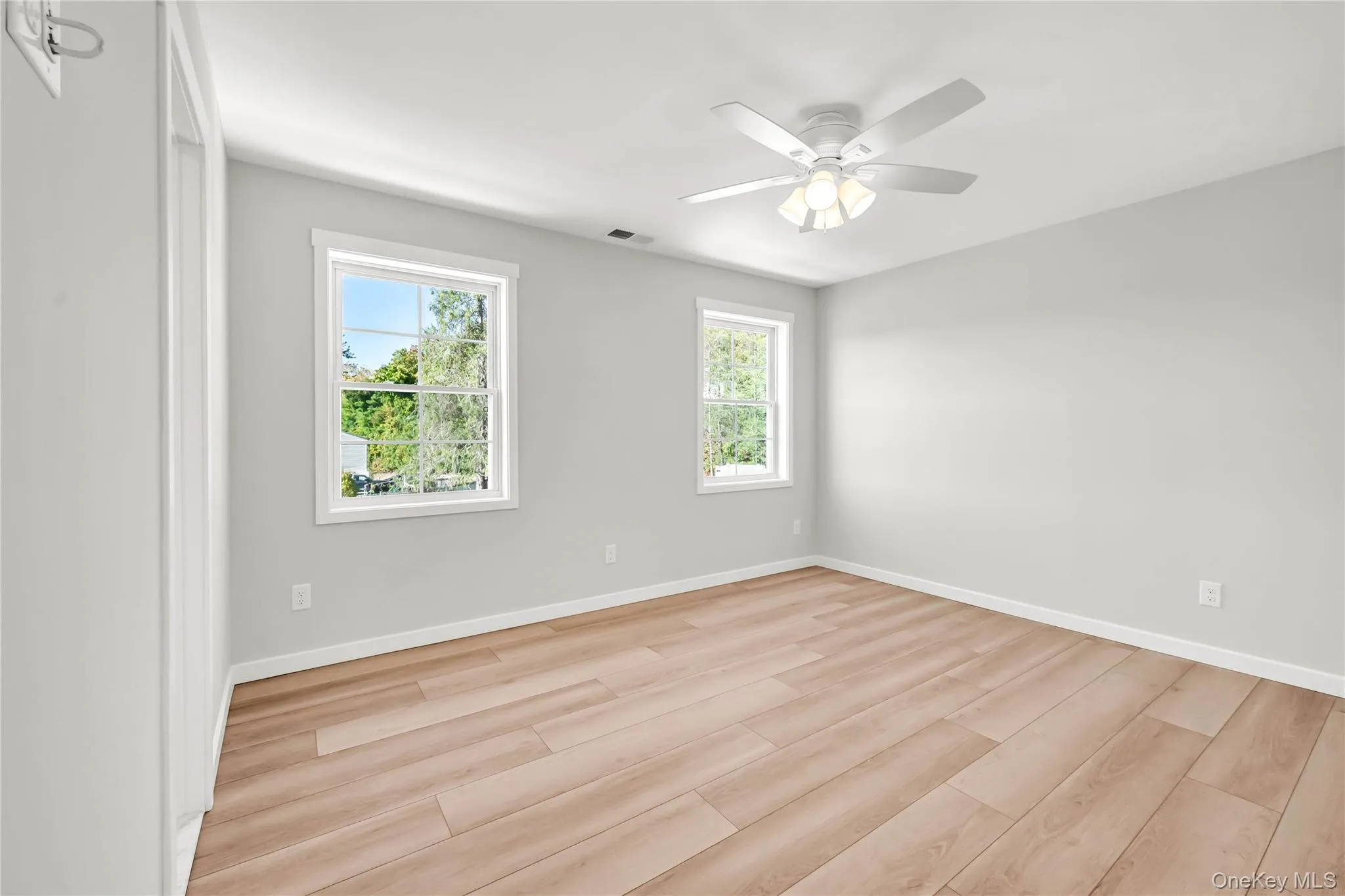 Empty room featuring light wood-style flooring and a ceiling fan Empty room featuring light wood-style flooring and a ceiling fan
