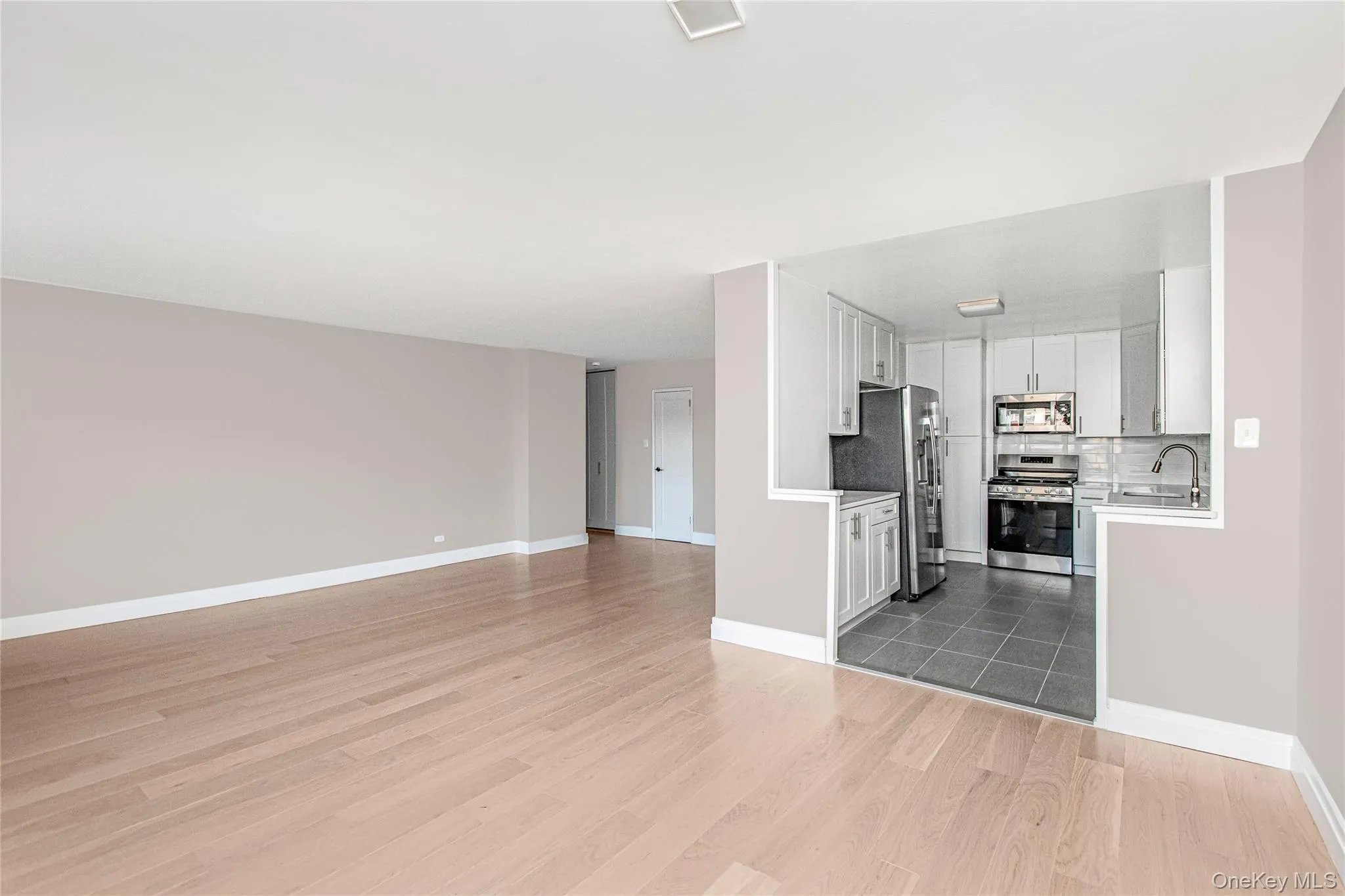 Unfurnished living room with light wood-style flooring and baseboards Unfurnished living room with light wood-style flooring and baseboards