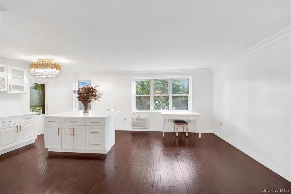 Kitchen featuring glass insert cabinets, dark wood-style floors, white cabinets, a kitchen island, and crown molding Kitchen featuring glass insert cabinets, dark wood-style floors, white cabinets, a kitchen island, and crown molding