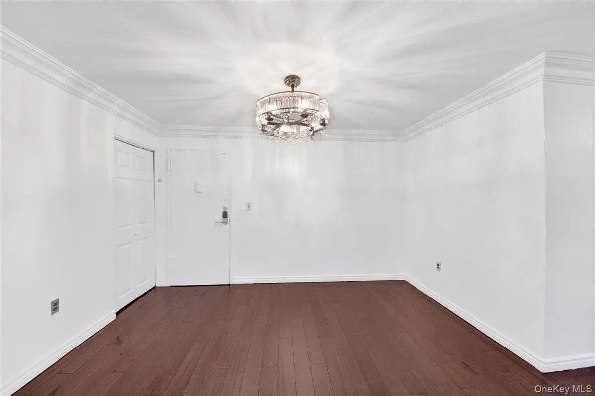 Unfurnished dining area featuring dark wood-type flooring, a chandelier, and crown molding Unfurnished dining area featuring dark wood-type flooring, a chandelier, and crown molding
