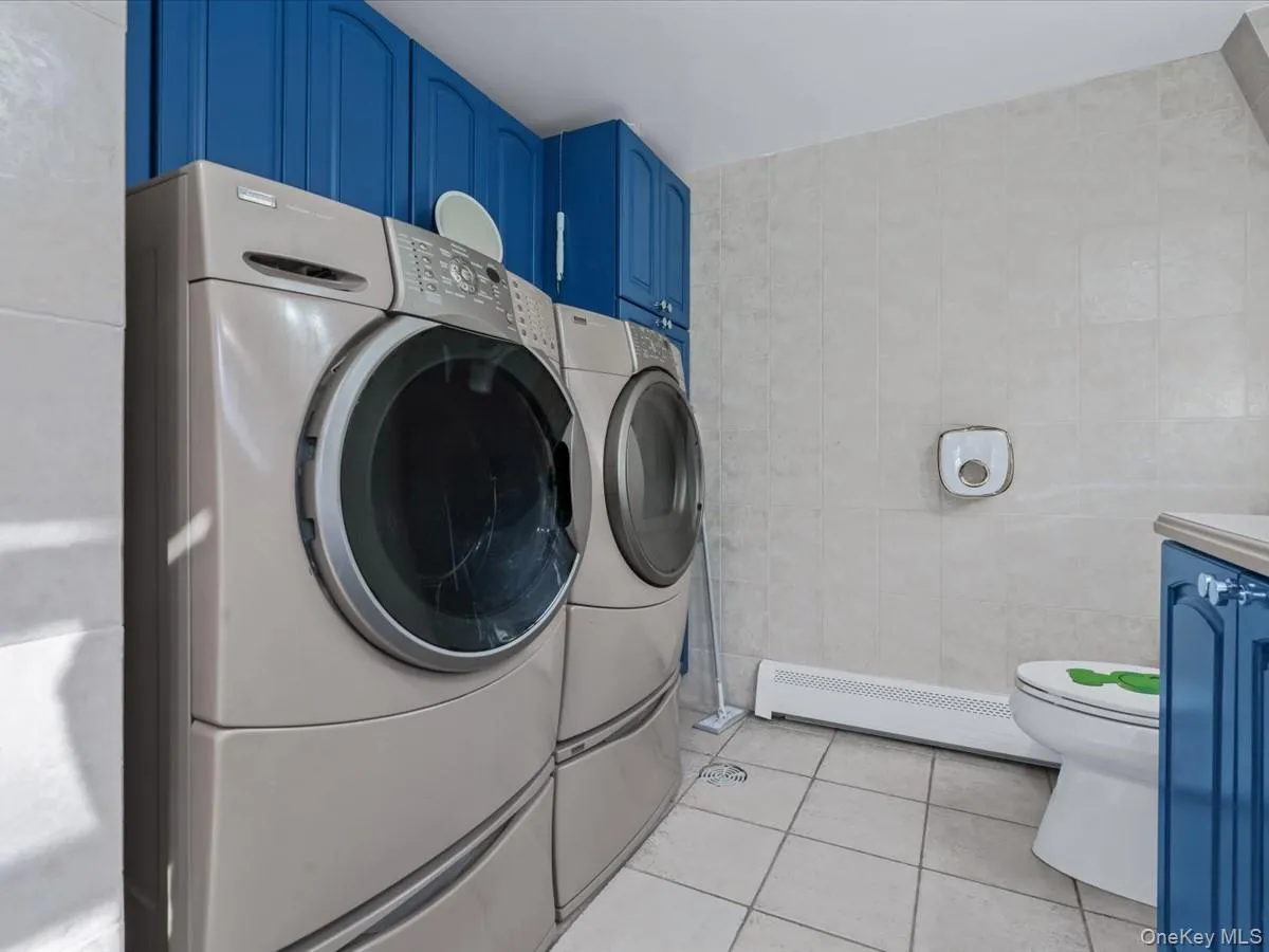 Washroom with light tile patterned floors, baseboard heating, separate washer and dryer, and tile walls Washroom with light tile patterned floors, baseboard heating, separate washer and dryer, and tile walls
