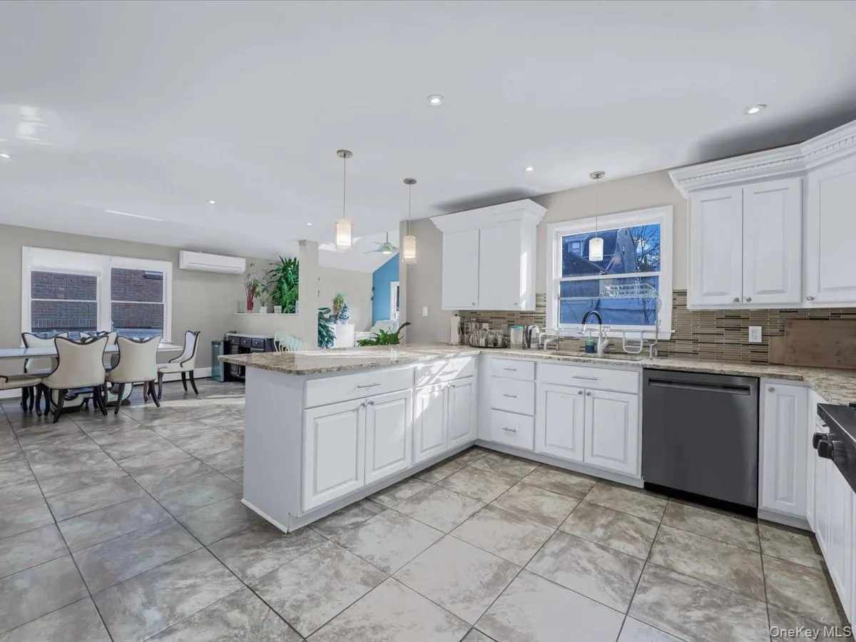 Kitchen with light stone counters, dishwasher, decorative light fixtures, white cabinets, and recessed lighting Kitchen with light stone counters, dishwasher, decorative light fixtures, white cabinets, and recessed lighting