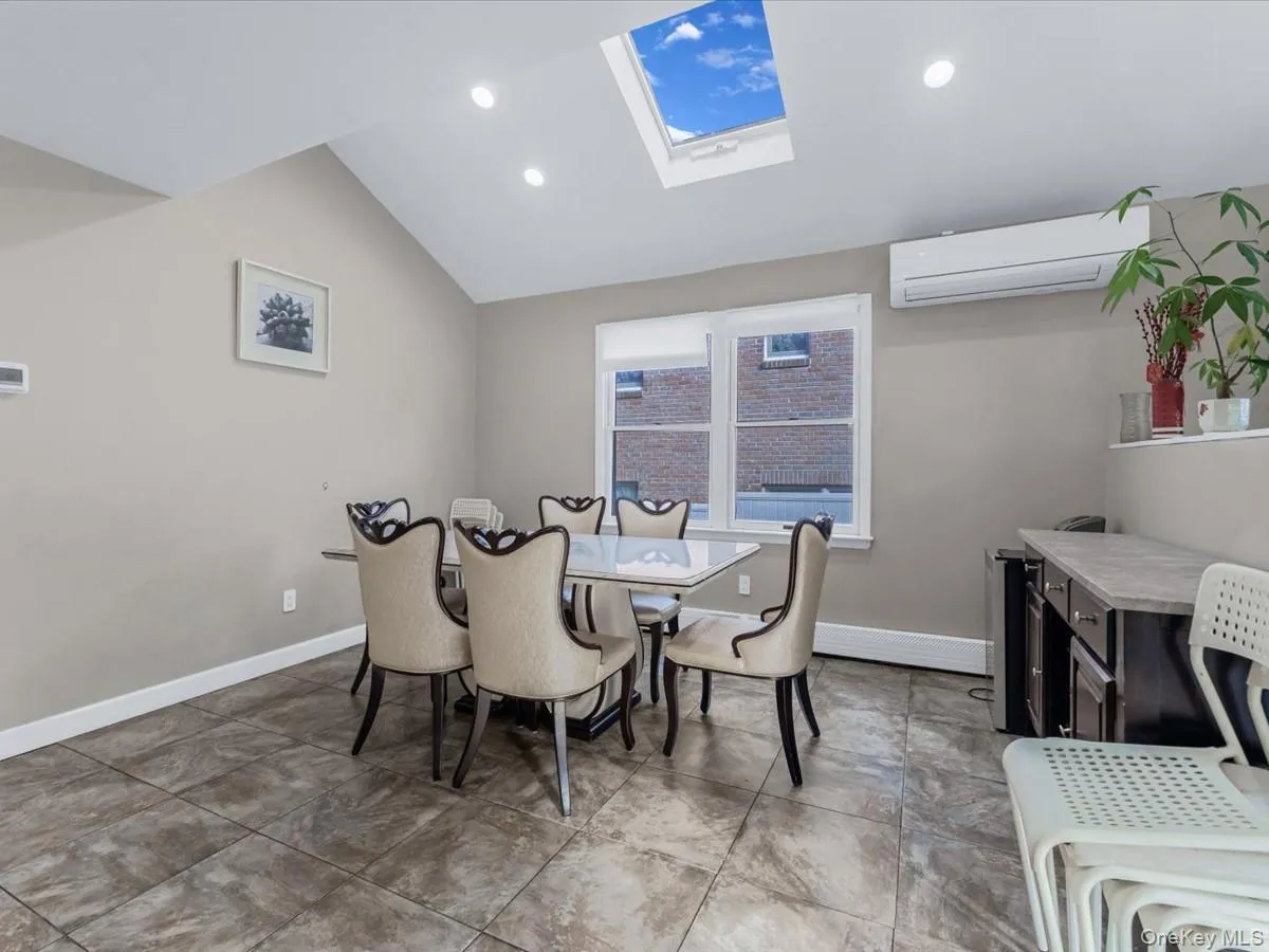 Dining space with a skylight, an AC wall unit, recessed lighting, lofted ceiling, and a baseboard heating unit Dining space with a skylight, an AC wall unit, recessed lighting, lofted ceiling, and a baseboard heating unit