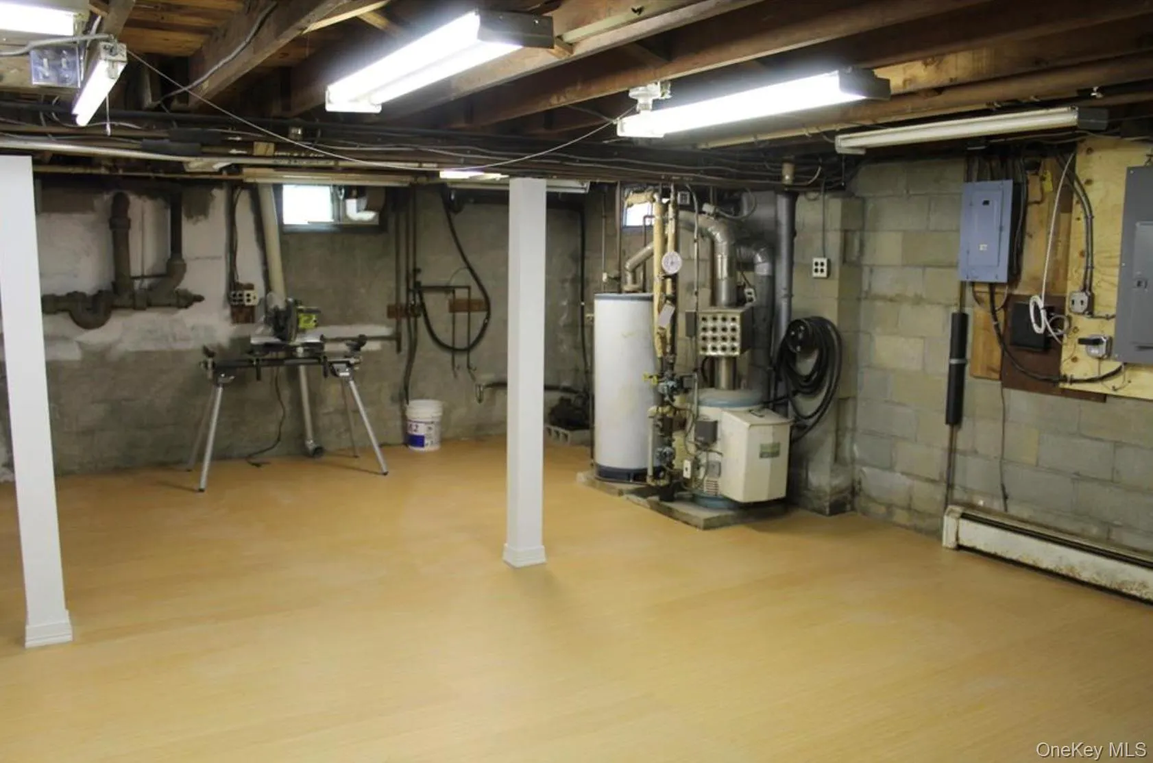 Unfinished basement featuring gas water heater, electric panel, and wood finished floors Unfinished basement featuring gas water heater, electric panel, and wood finished floors