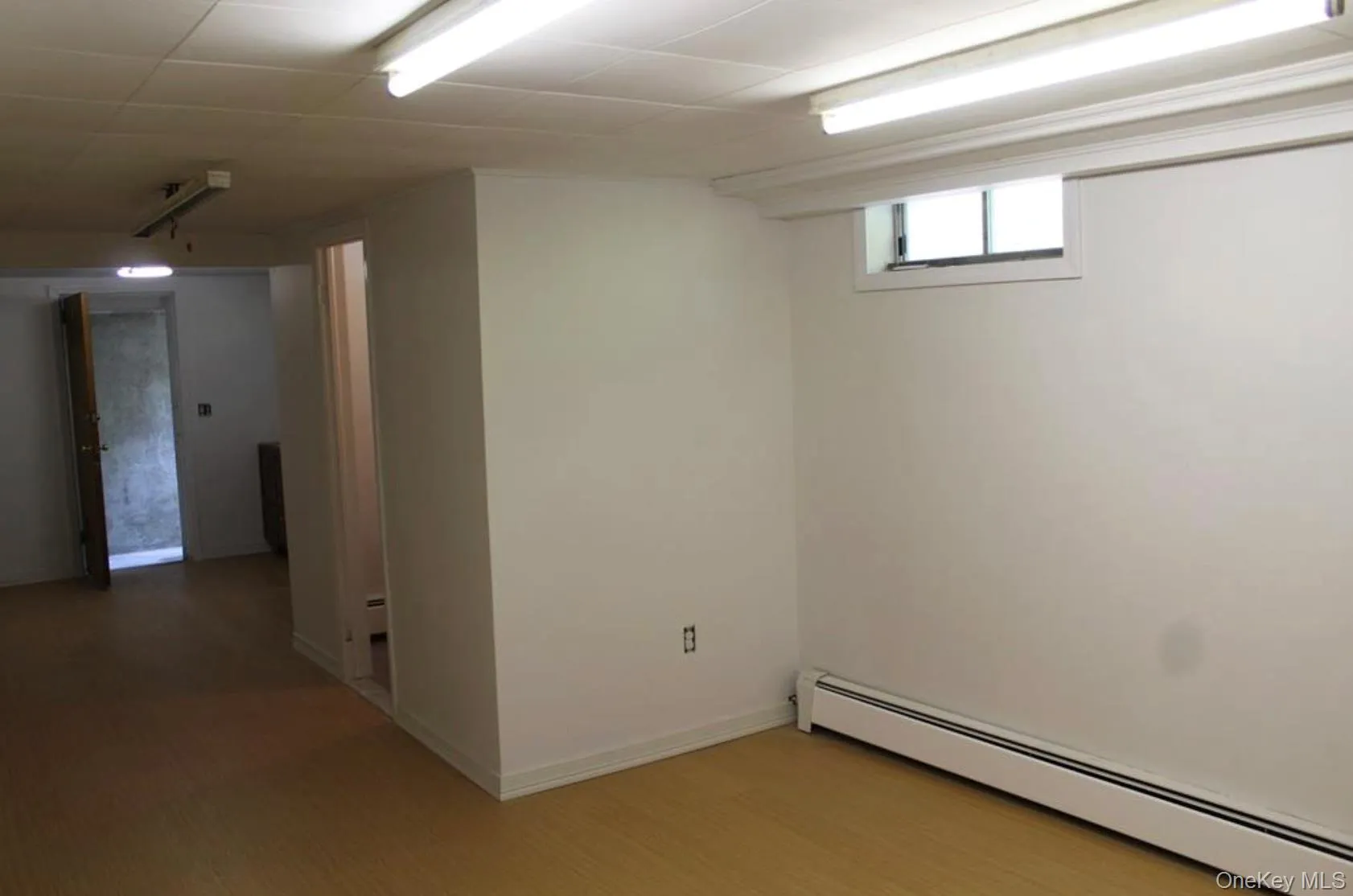 Basement with a baseboard heating unit and wood finished floors Basement with a baseboard heating unit and wood finished floors