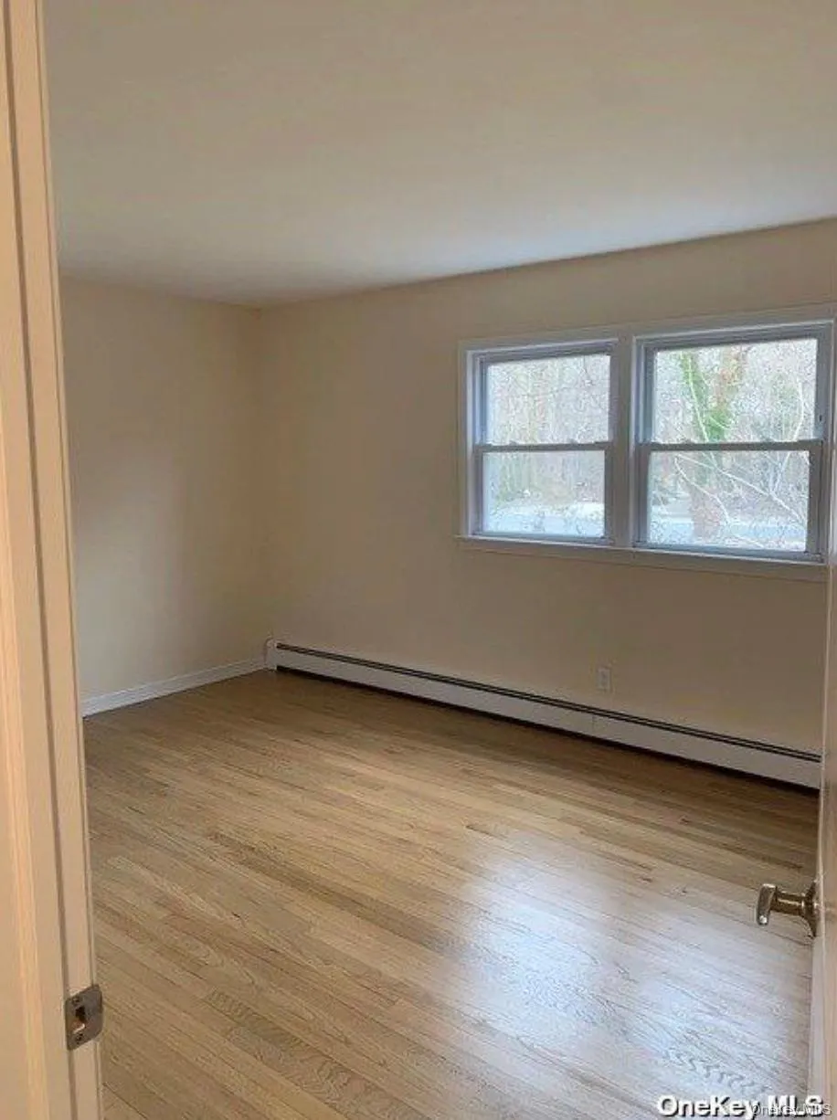 Empty room with a baseboard radiator and light wood-style floors Empty room with a baseboard radiator and light wood-style floors