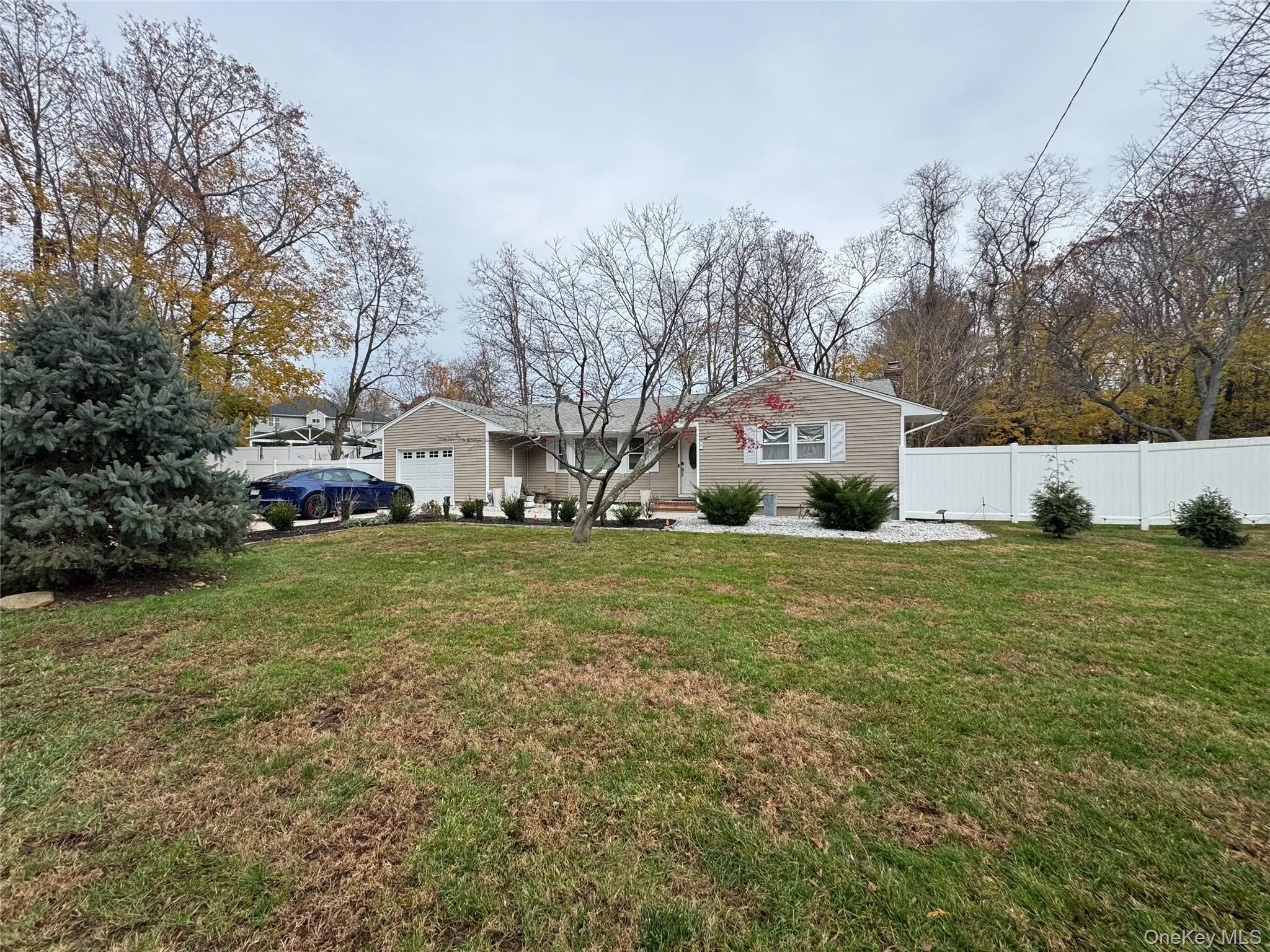 Ranch-style house with a chimney, an attached garage, and view of wooded area Ranch-style house with a chimney, an attached garage, and view of wooded area