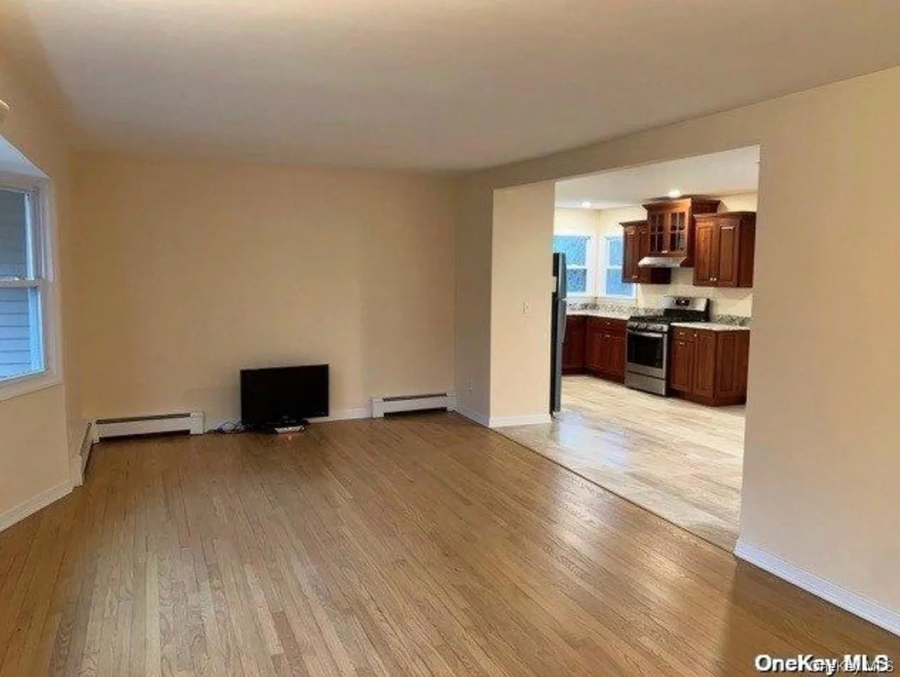 Unfurnished living room featuring light wood-style floors, baseboard heating, and a baseboard radiator Unfurnished living room featuring light wood-style floors, baseboard heating, and a baseboard radiator