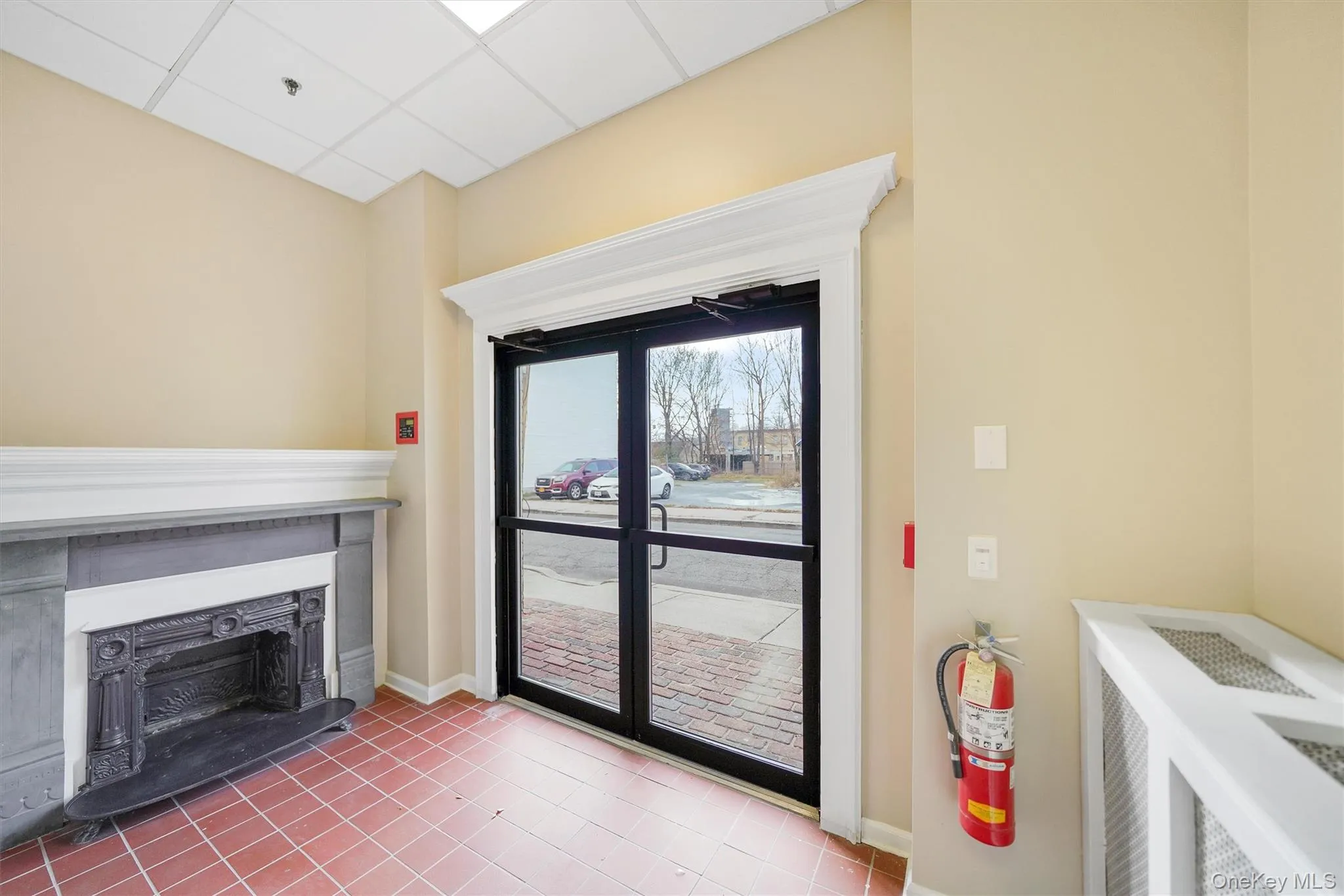 Living room with light tile patterned floors, a fireplace, and a drop ceiling Living room with light tile patterned floors, a fireplace, and a drop ceiling