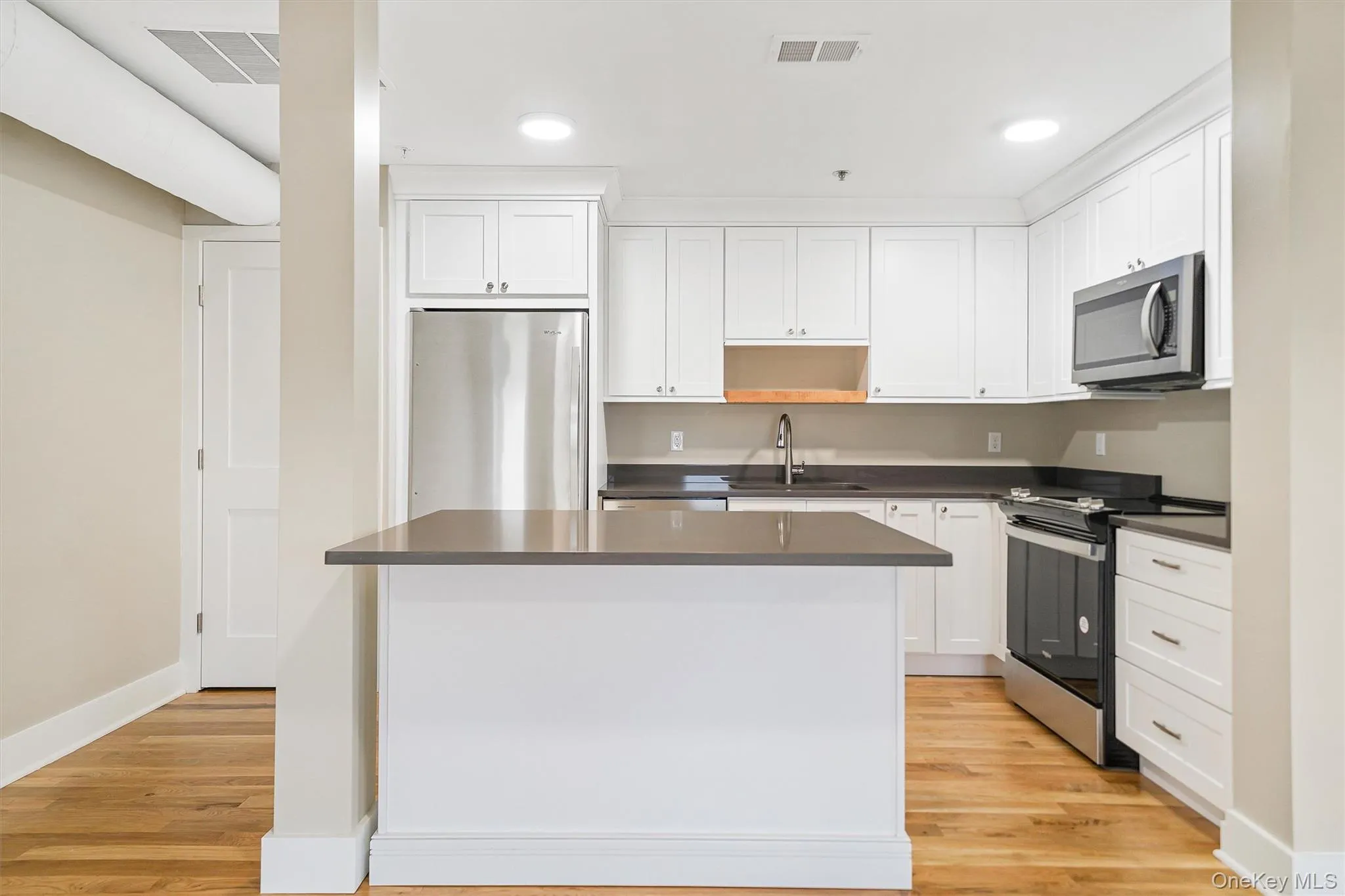 Kitchen with stainless steel appliances, white cabinets, light wood-style flooring, recessed lighting, and open shelves Kitchen with stainless steel appliances, white cabinets, light wood-style flooring, recessed lighting, and open shelves