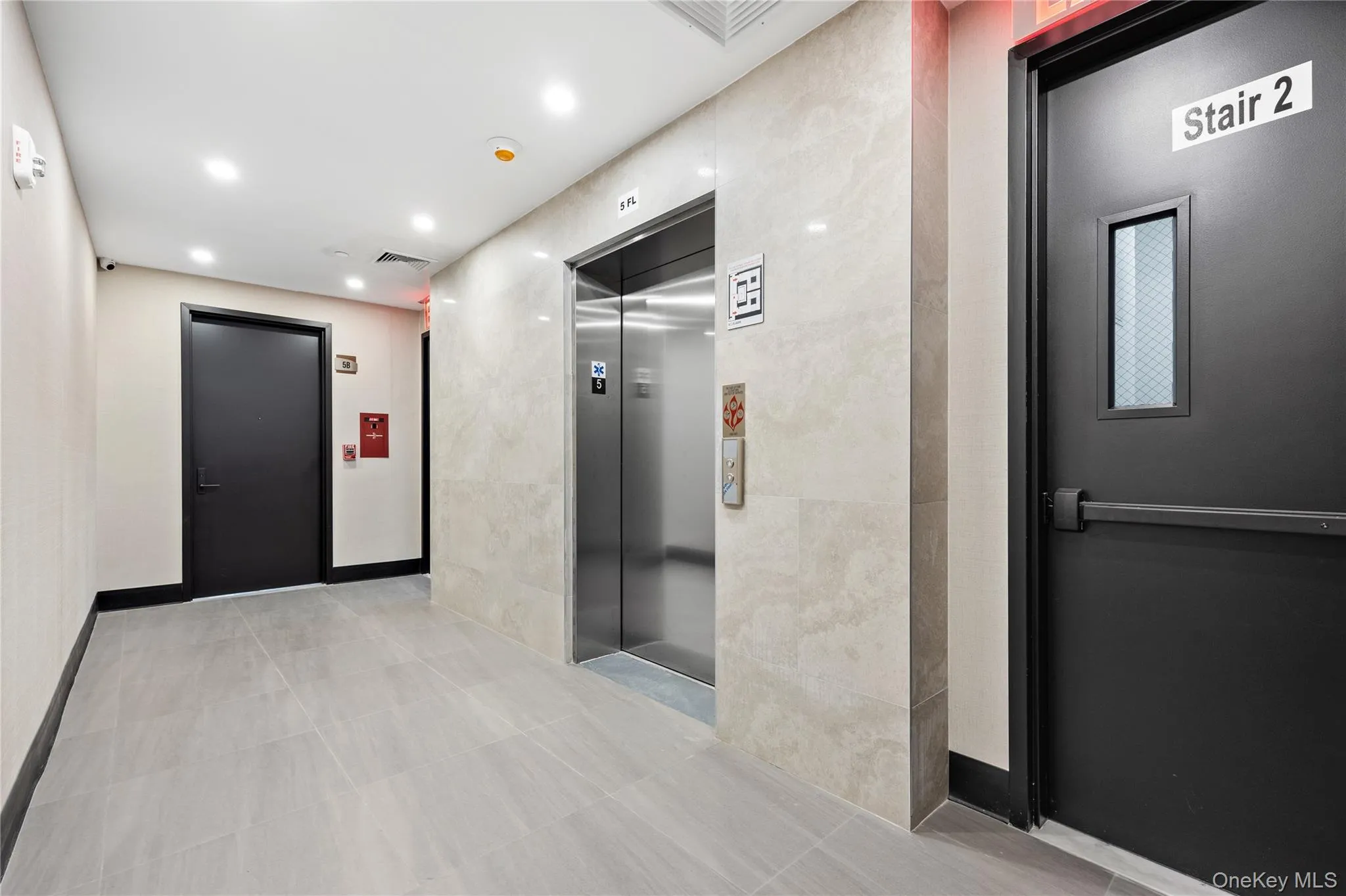 Hall with elevator, recessed lighting, tile walls, and tile patterned flooring Hall with elevator, recessed lighting, tile walls, and tile patterned flooring