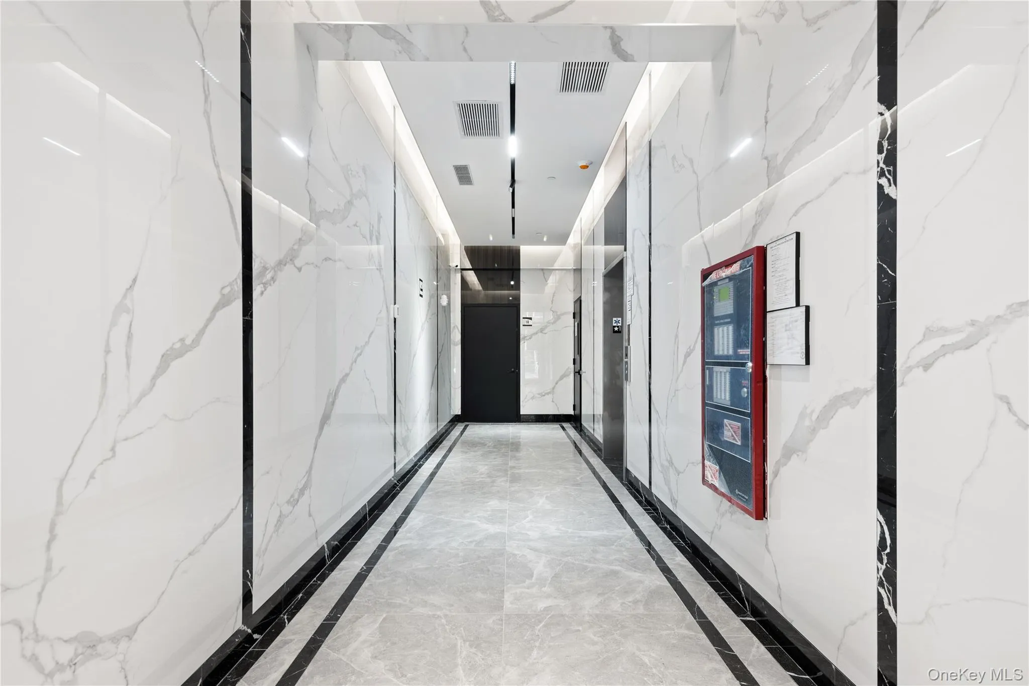 Hallway featuring light marble finish floors and stone wall Hallway featuring light marble finish floors and stone wall
