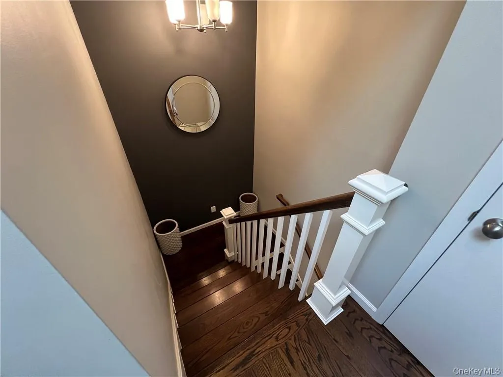 Stairs with a notable chandelier and hardwood / wood-style floors Stairs with a notable chandelier and hardwood / wood-style floors