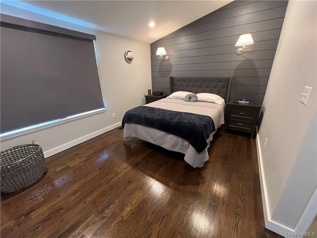 Bedroom with wooden walls, dark hardwood / wood-style floors, and vaulted ceiling Bedroom with wooden walls, dark hardwood / wood-style floors, and vaulted ceiling