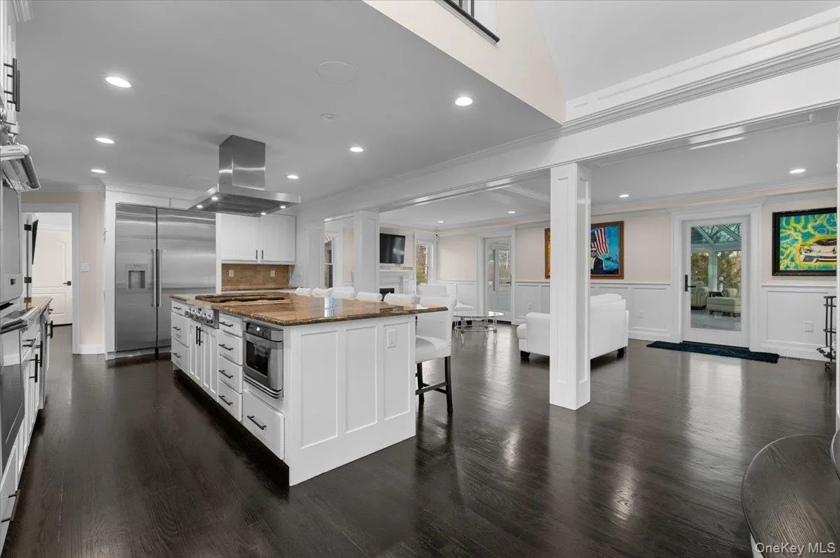 Kitchen with a kitchen breakfast bar, dark stone counters, recessed lighting, appliances with stainless steel finishes, and white cabinets Kitchen with a kitchen breakfast bar, dark stone counters, recessed lighting, appliances with stainless steel finishes, and white cabinets