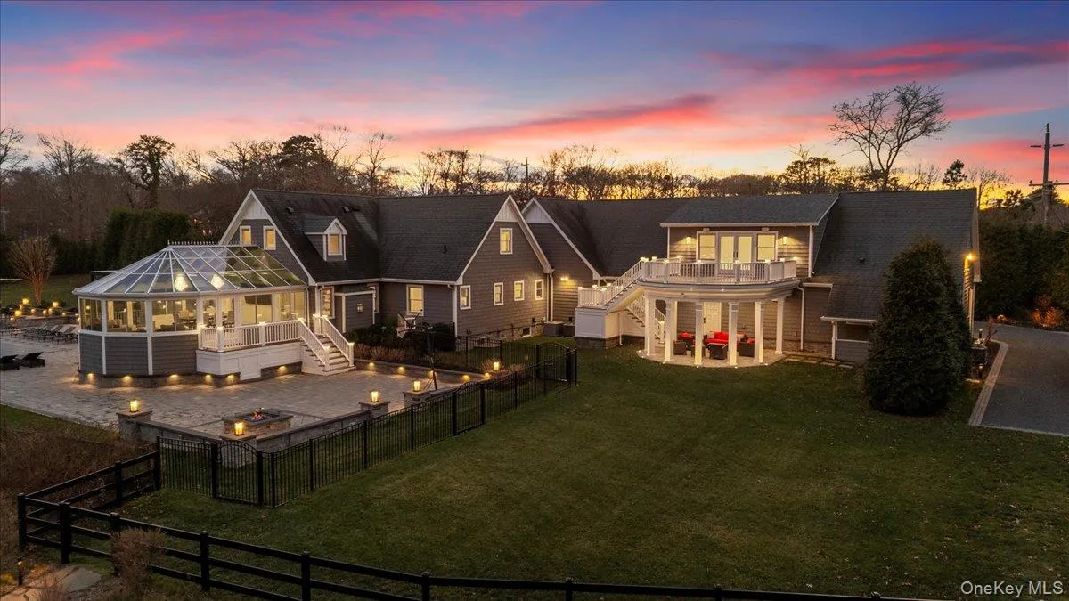 Back of property at dusk with stairs, a patio area, an outdoor fire pit, a fenced backyard, and a sunroom Back of property at dusk with stairs, a patio area, an outdoor fire pit, a fenced backyard, and a sunroom