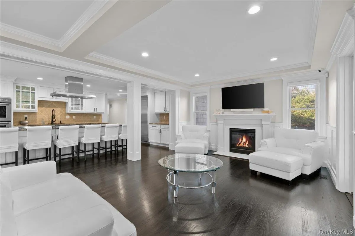 Living room with dark wood-style floors, a glass covered fireplace, recessed lighting, and crown molding Living room with dark wood-style floors, a glass covered fireplace, recessed lighting, and crown molding