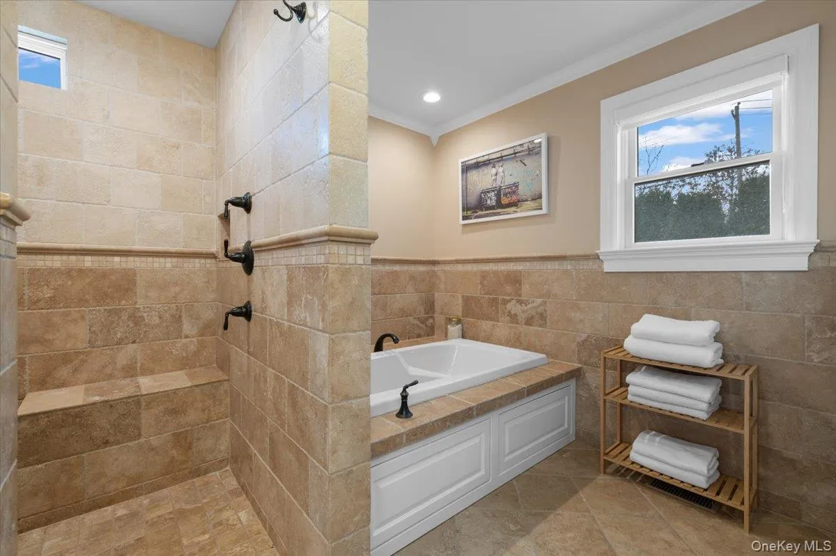 Bathroom with tile walls, healthy amount of natural light, a wainscoted wall, a garden tub, and crown molding Bathroom with tile walls, healthy amount of natural light, a wainscoted wall, a garden tub, and crown molding