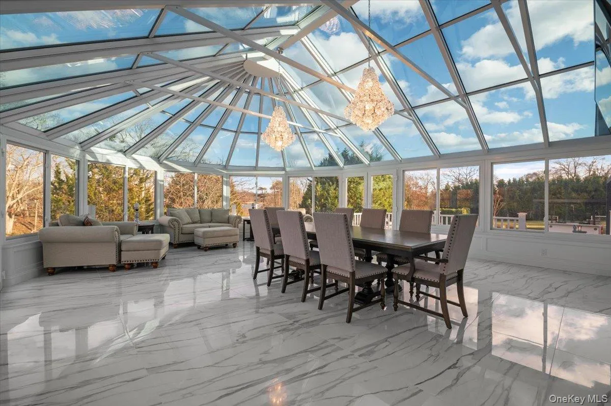 Sunroom / solarium featuring marble tiled flooring, high vaulted ceiling, a decorative wall, and a chandelier Sunroom / solarium featuring marble tiled flooring, high vaulted ceiling, a decorative wall, and a chandelier
