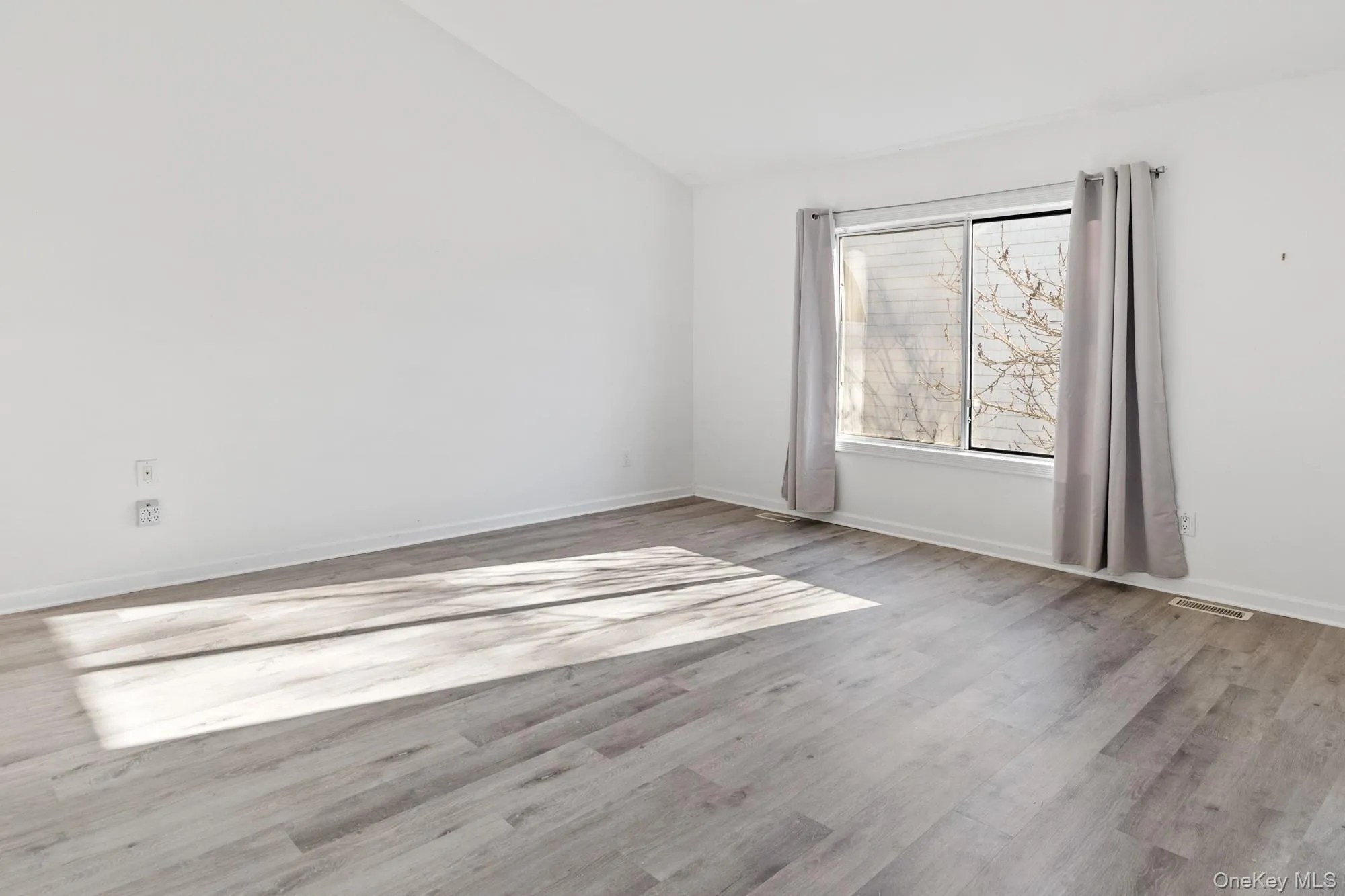 Primary bedroom with lofted ceiling and light wood-style floors Primary bedroom with lofted ceiling and light wood-style floors