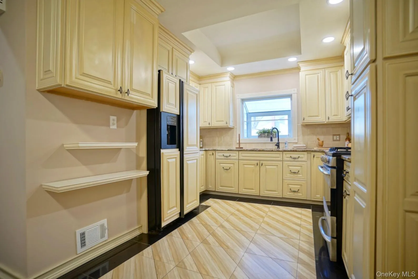 Kitchen featuring recessed lighting, stainless steel range, a raised ceiling, paneled fridge, and backsplash Kitchen featuring recessed lighting, stainless steel range, a raised ceiling, paneled fridge, and backsplash