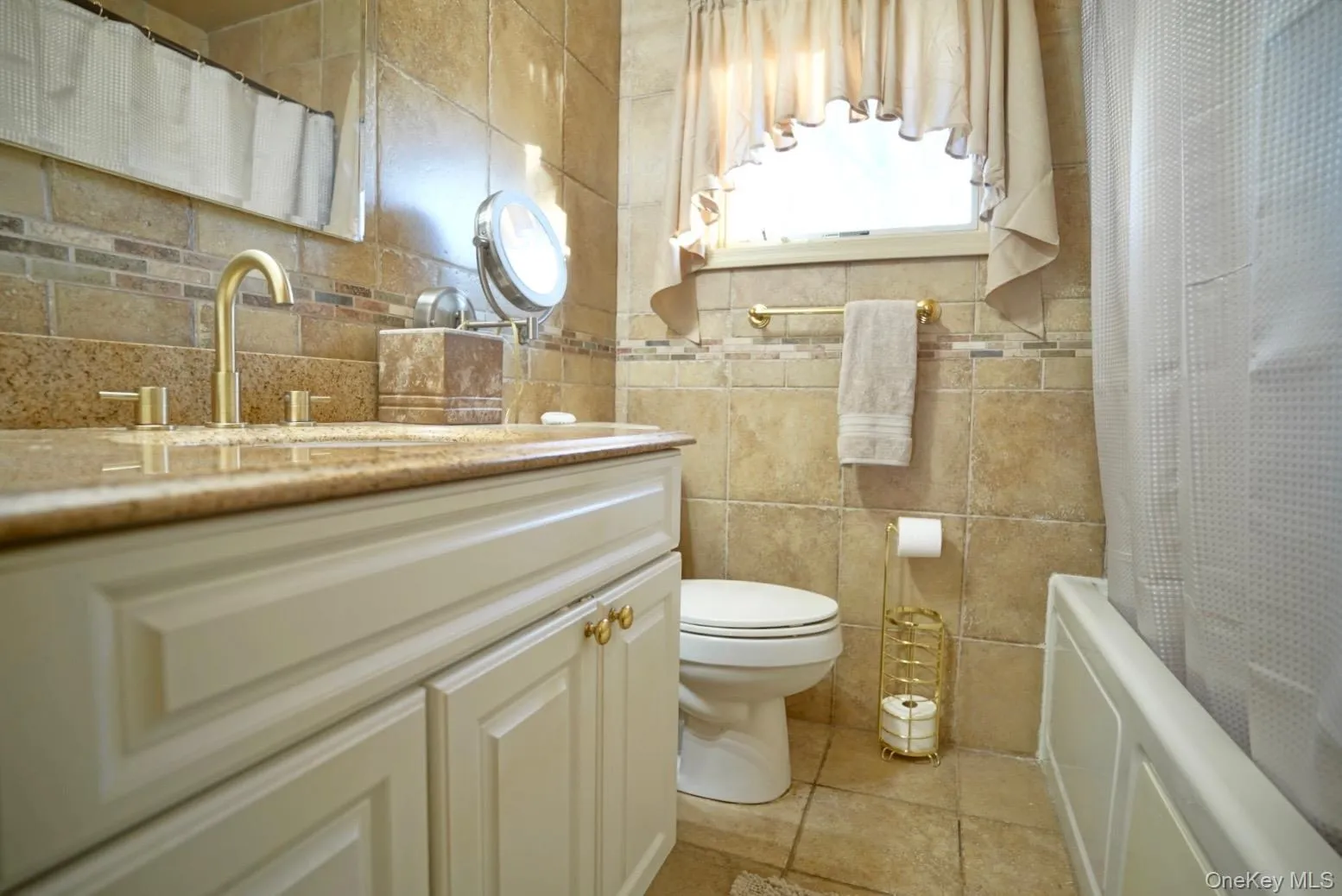 Full bath featuring vanity, shower / bathtub combination with curtain, and tile walls Full bath featuring vanity, shower / bathtub combination with curtain, and tile walls