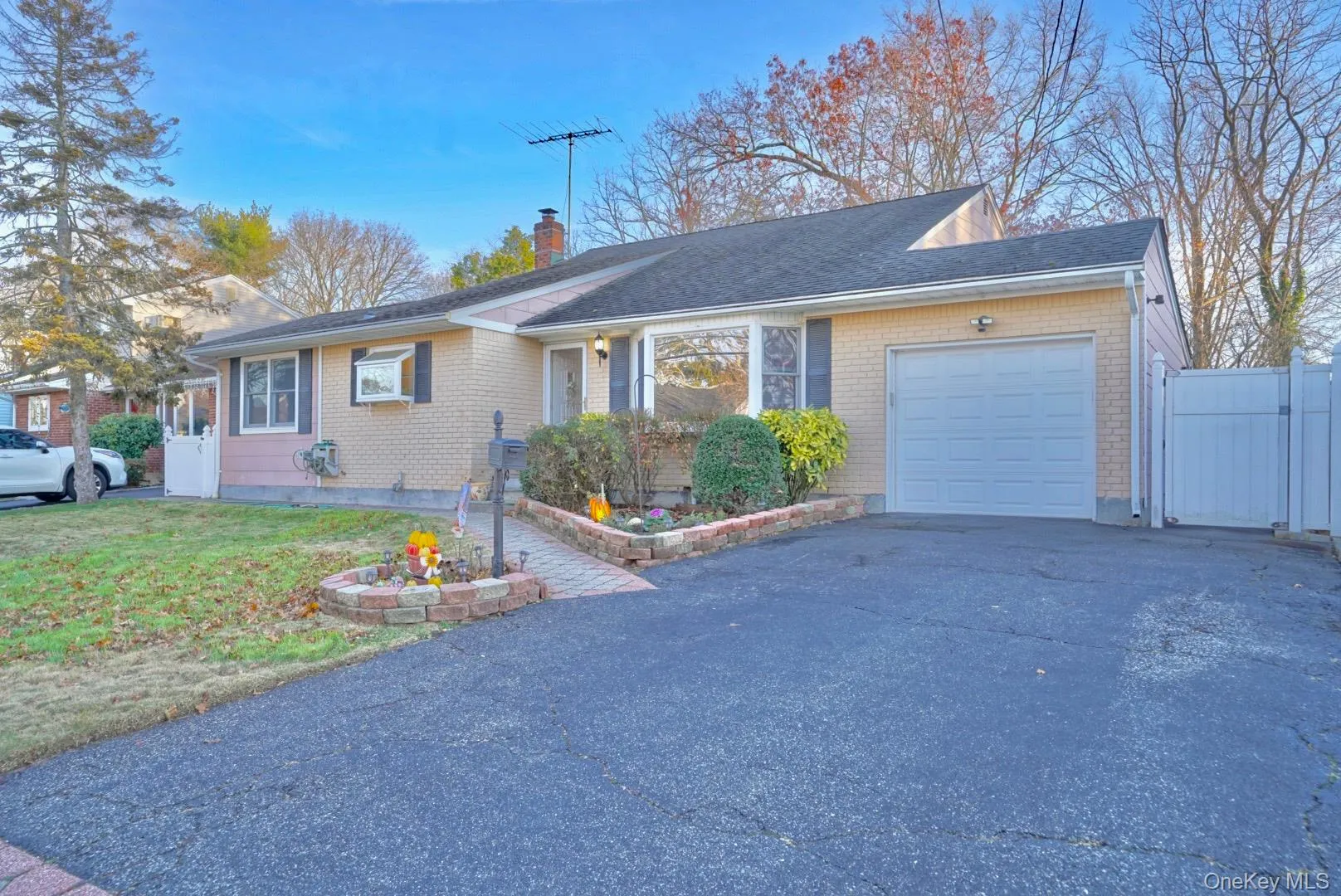 Ranch-style home with a garage, asphalt driveway, brick siding, and a chimney Ranch-style home with a garage, asphalt driveway, brick siding, and a chimney