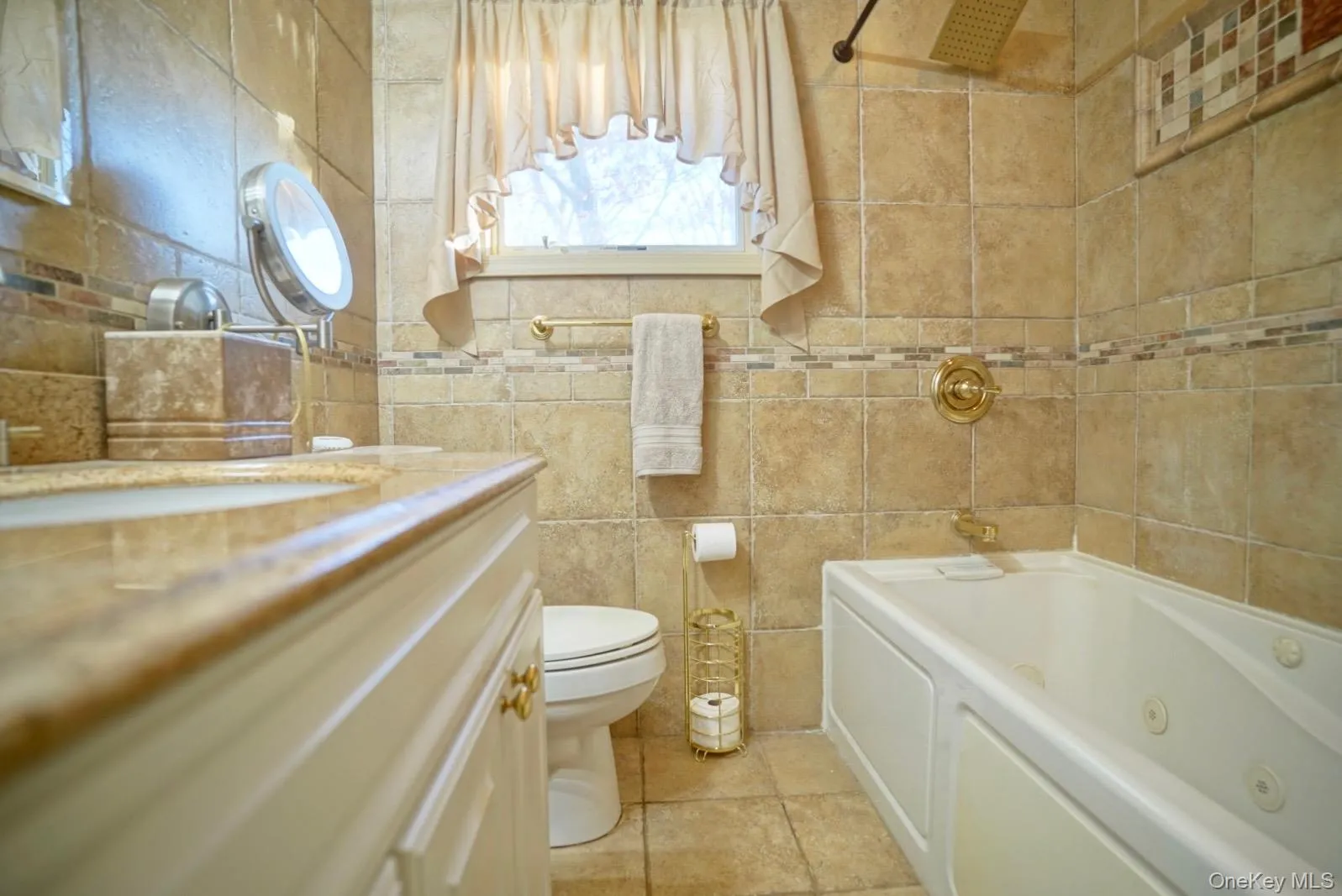Bathroom featuring a combined bath / shower with jetted tub, vanity, tile walls, and light tile patterned floors Bathroom featuring a combined bath / shower with jetted tub, vanity, tile walls, and light tile patterned floors