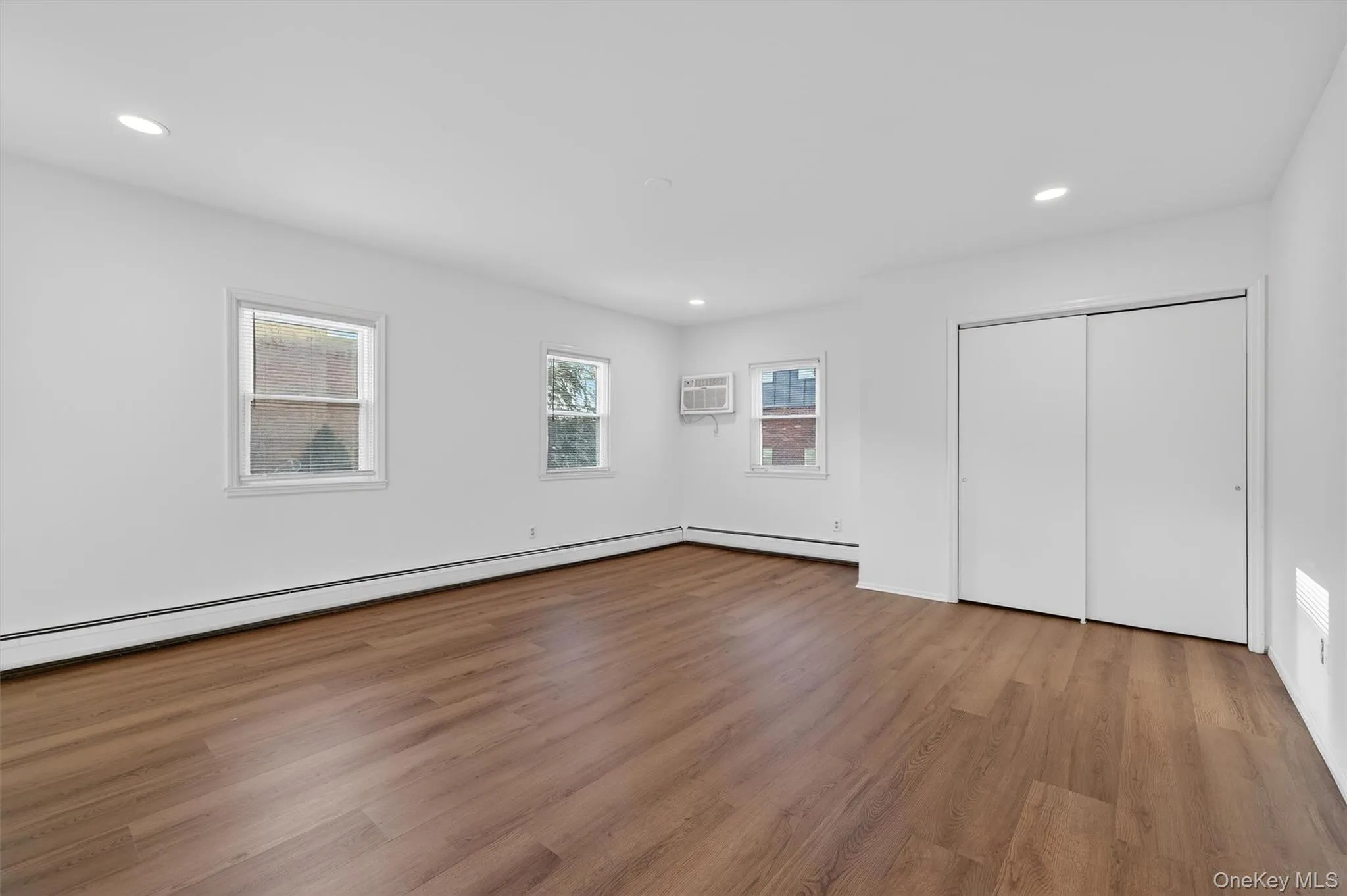 Unfurnished bedroom featuring light wood finished floors, recessed lighting, baseboard heating, and a closet Unfurnished bedroom featuring light wood finished floors, recessed lighting, baseboard heating, and a closet
