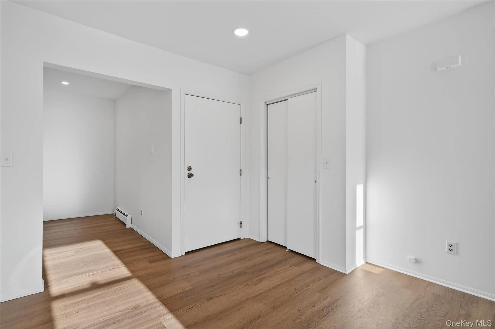 Unfurnished bedroom featuring wood finished floors, recessed lighting, a baseboard radiator, and a closet Unfurnished bedroom featuring wood finished floors, recessed lighting, a baseboard radiator, and a closet