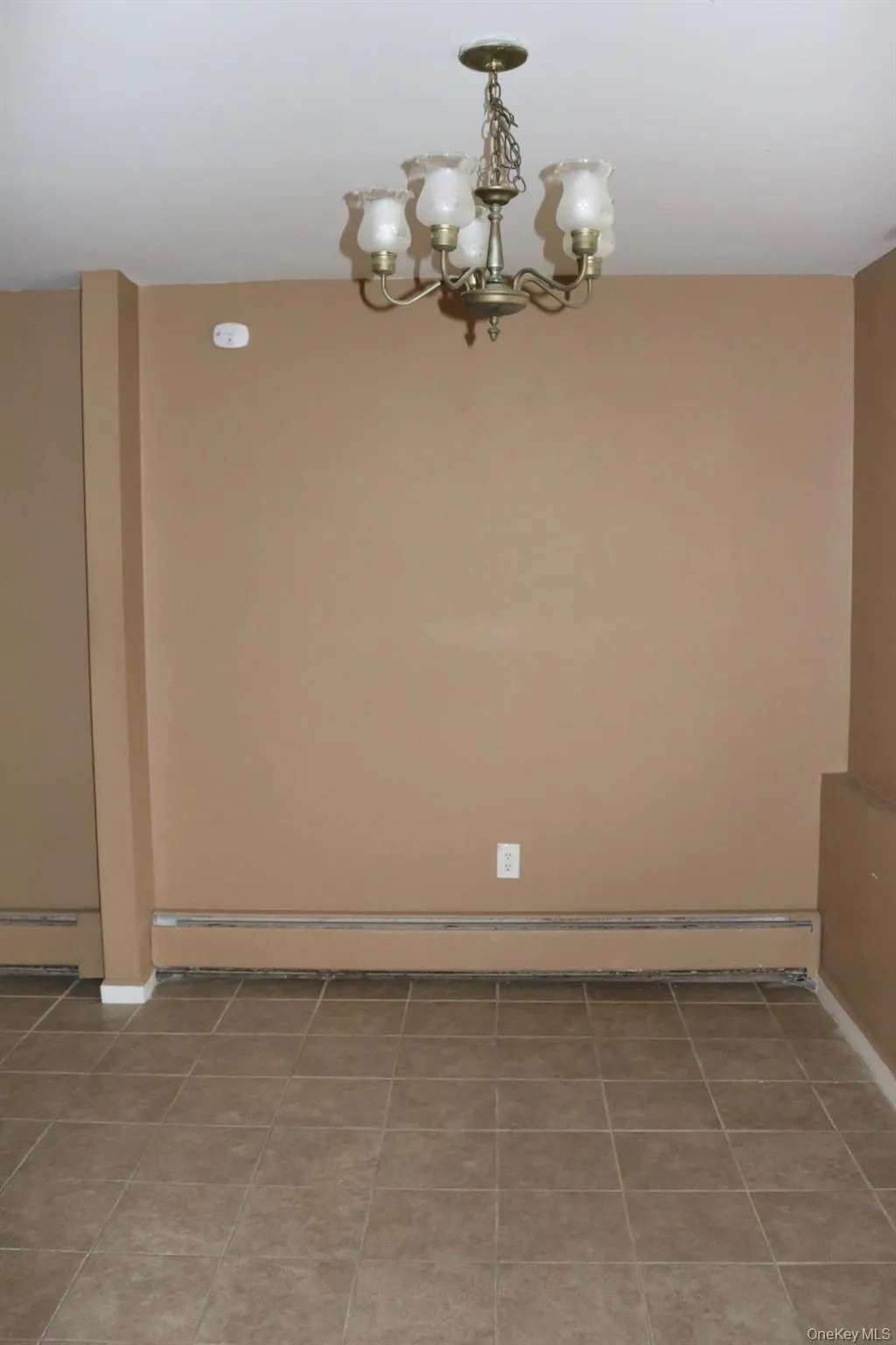 Spare room with baseboard heating and a chandelier Spare room with baseboard heating and a chandelier