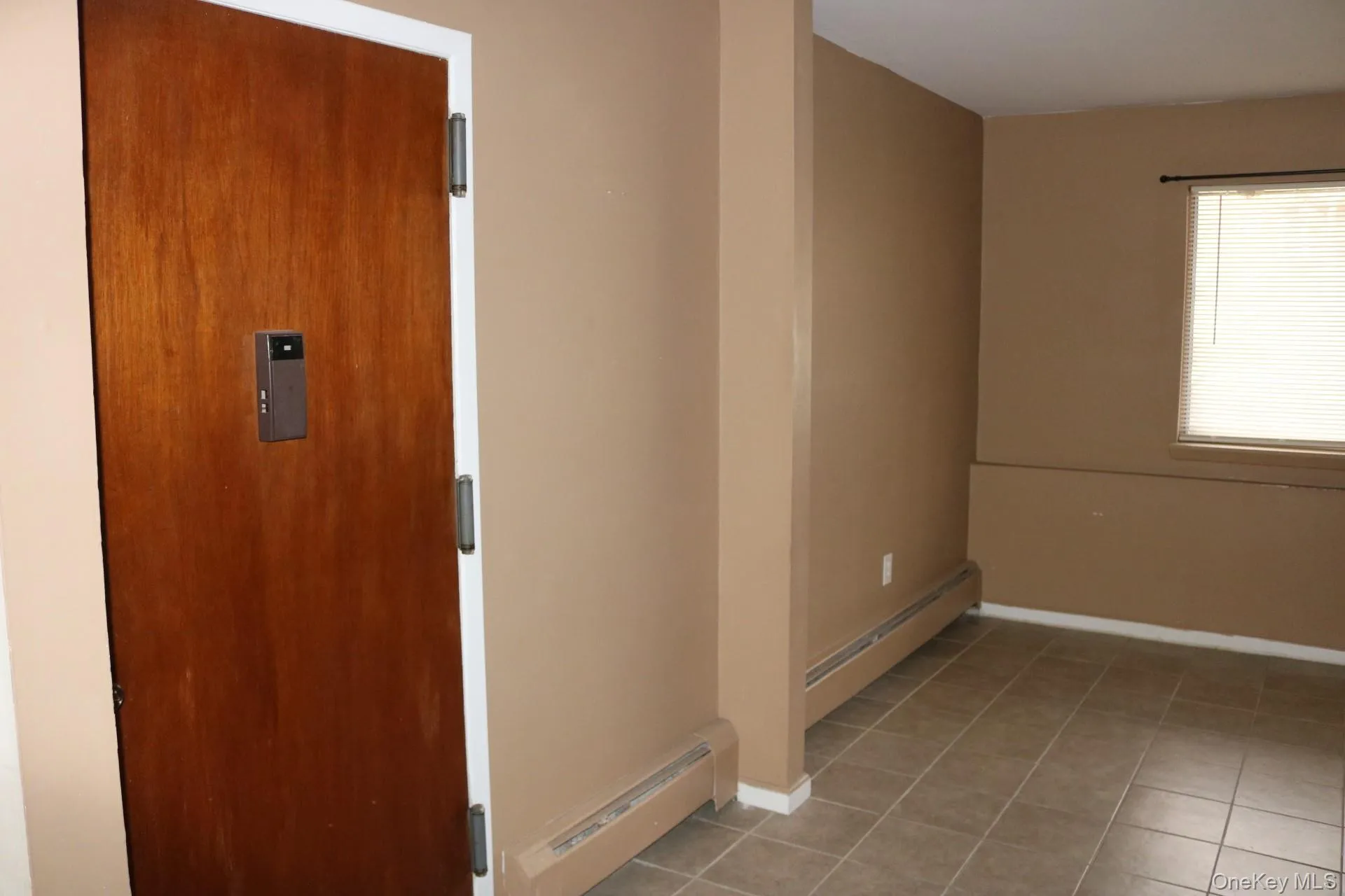 Tiled empty room with a baseboard radiator Tiled empty room with a baseboard radiator