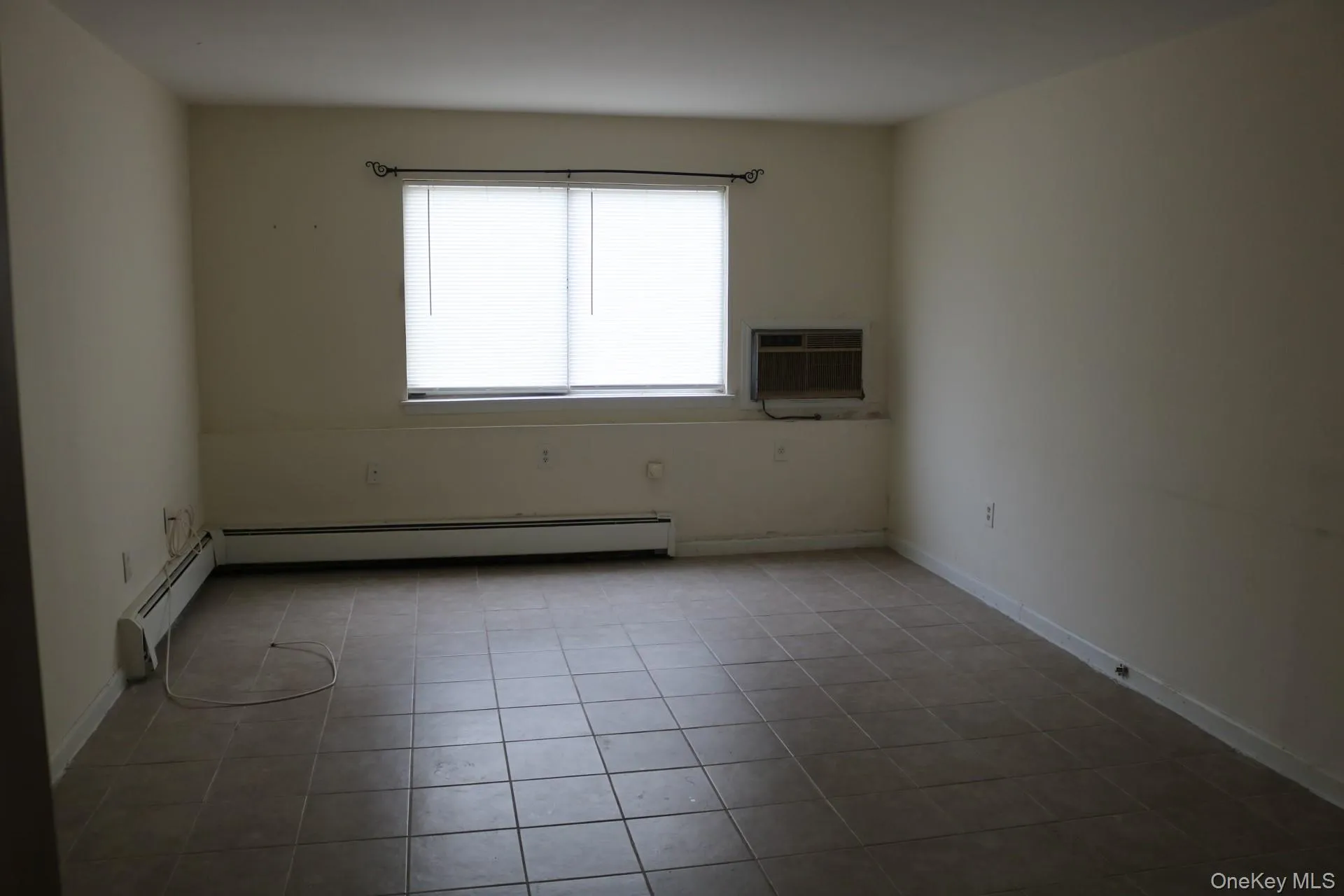 Spare room featuring light tile patterned floors, baseboard heating, and a wall mounted AC Spare room featuring light tile patterned floors, baseboard heating, and a wall mounted AC