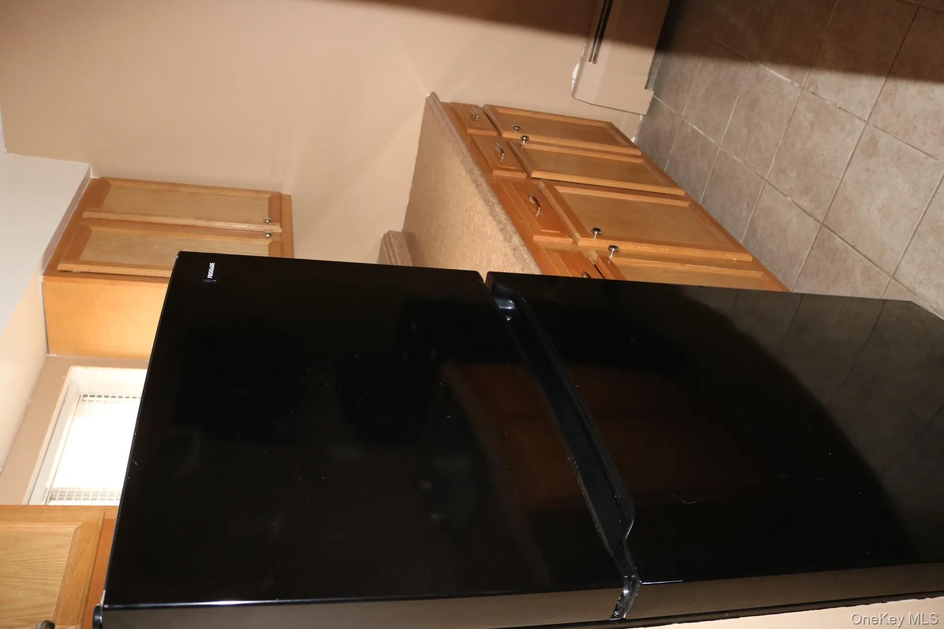 Kitchen featuring black refrigerator, light tile patterned floors, and a baseboard radiator Kitchen featuring black refrigerator, light tile patterned floors, and a baseboard radiator