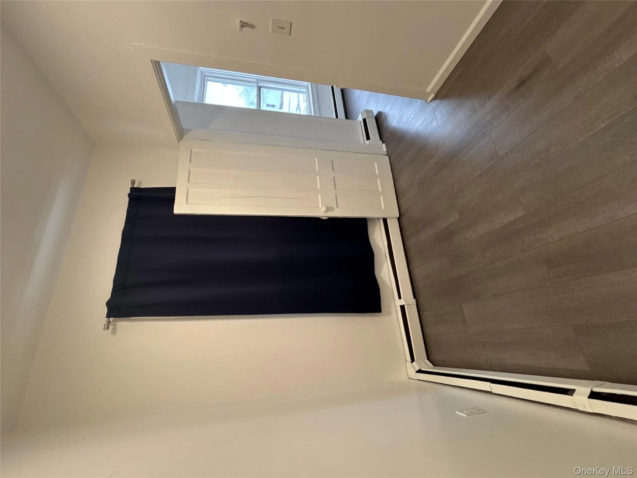 Unfurnished room with baseboard heating and dark wood finished floors Unfurnished room with baseboard heating and dark wood finished floors