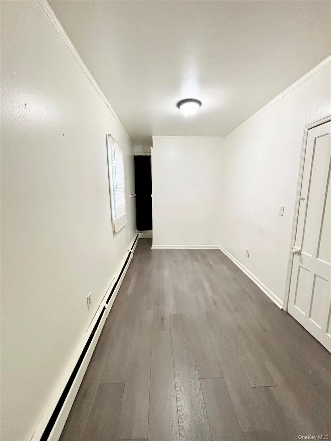 Unfurnished room with a baseboard radiator, hardwood / wood-style floors, and ornamental molding Unfurnished room with a baseboard radiator, hardwood / wood-style floors, and ornamental molding