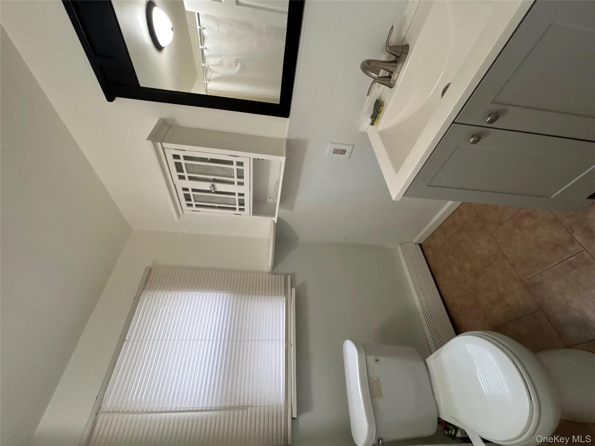 Full bathroom with a baseboard radiator, vanity, curtained shower, and dark tile patterned flooring Full bathroom with a baseboard radiator, vanity, curtained shower, and dark tile patterned flooring