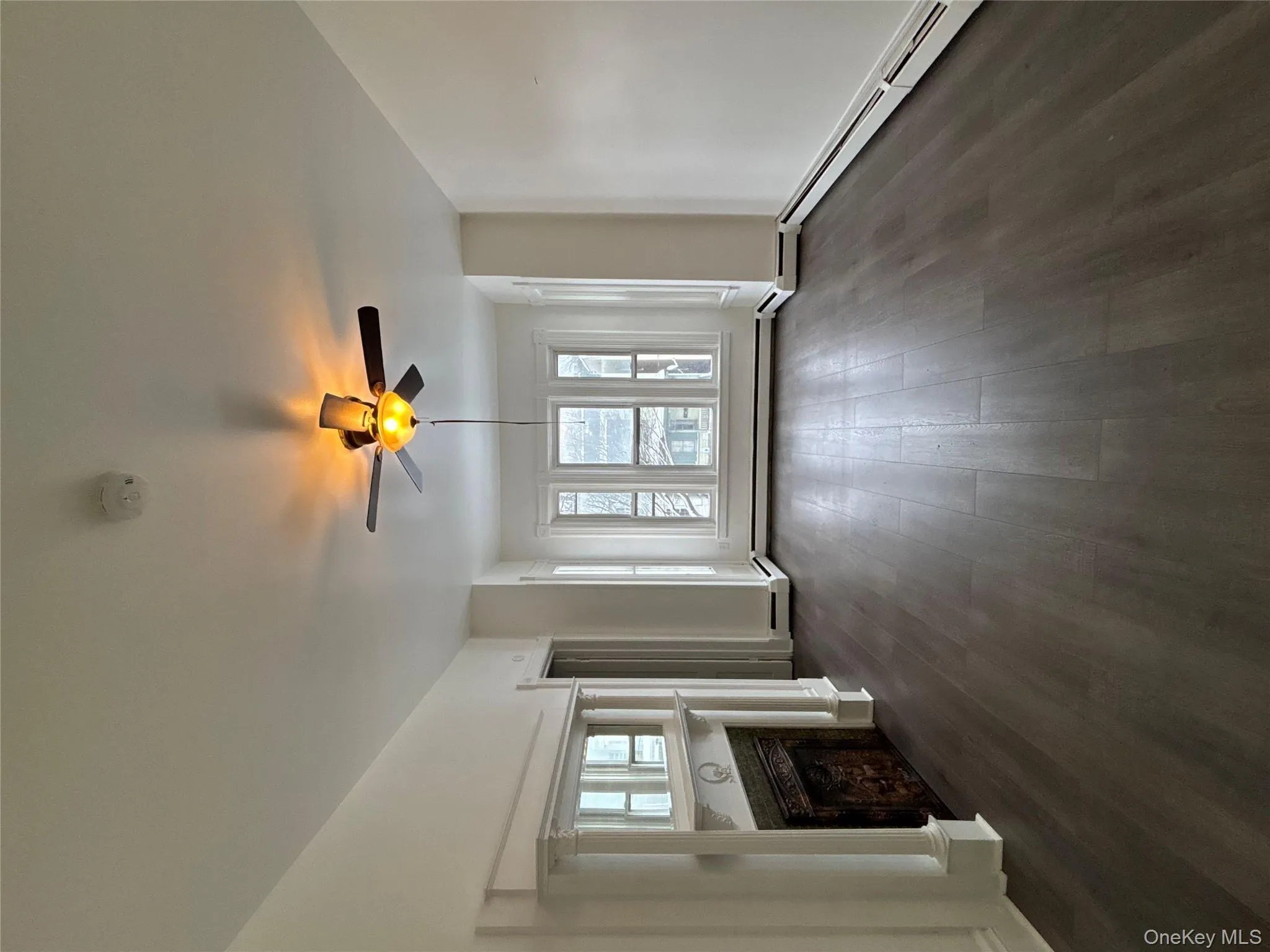 Unfurnished living room with dark wood finished floors, ceiling fan, a fireplace, and baseboard heating Unfurnished living room with dark wood finished floors, ceiling fan, a fireplace, and baseboard heating