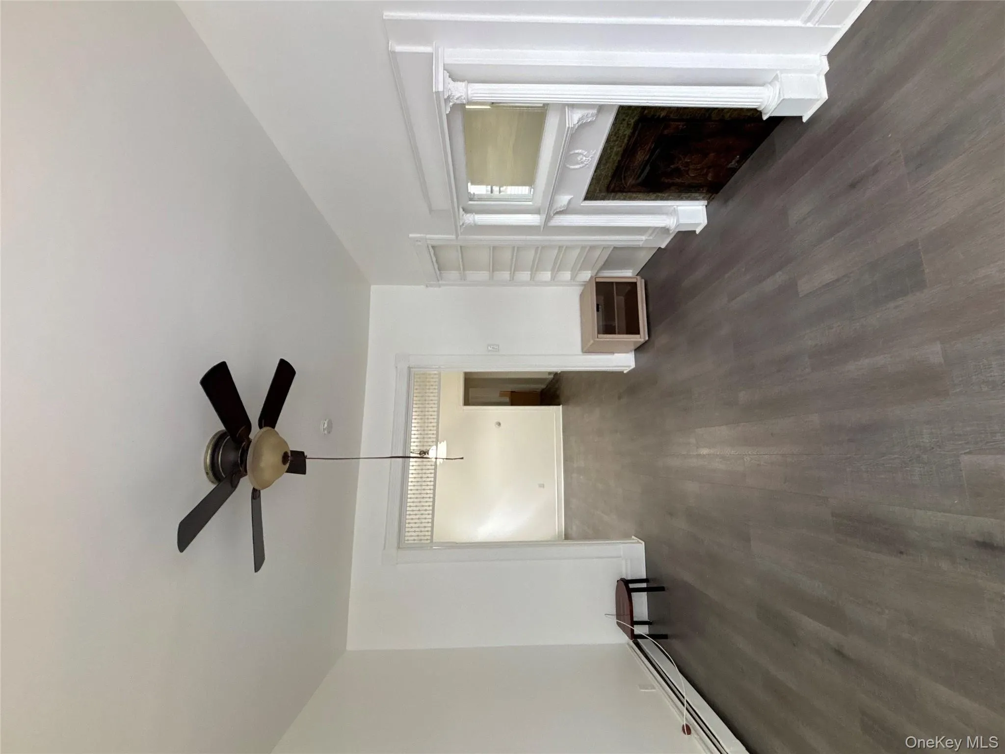 Unfurnished living room with baseboard heating, dark wood finished floors, built in features, a fireplace, and a ceiling fan Unfurnished living room with baseboard heating, dark wood finished floors, built in features, a fireplace, and a ceiling fan