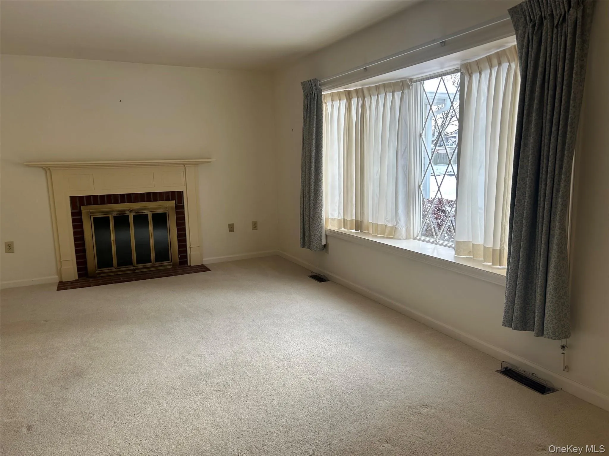 Unfurnished living room with a brick fireplace and carpet floors Unfurnished living room with a brick fireplace and carpet floors