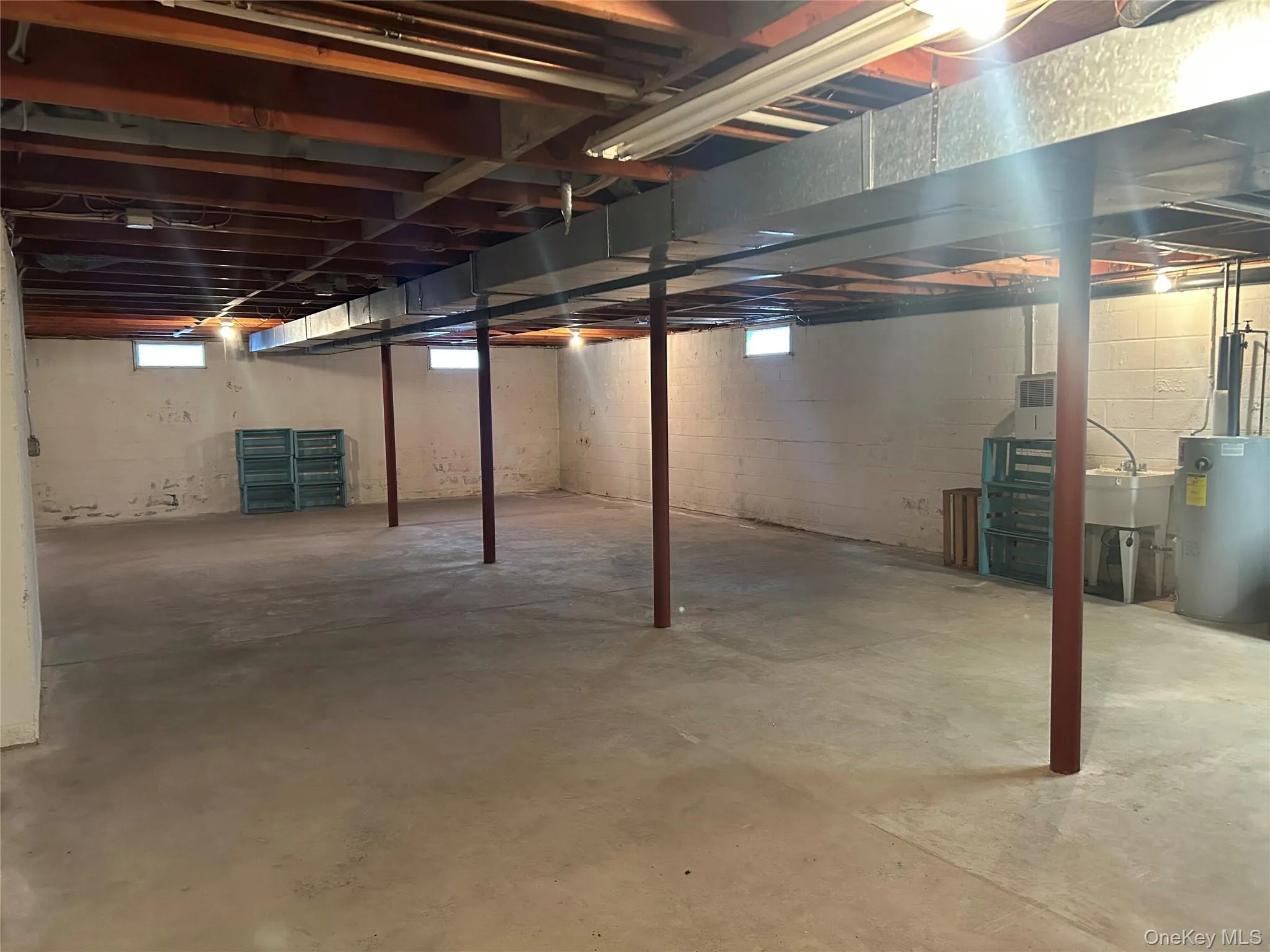 Below grade area featuring electric water heater and a sink Below grade area featuring electric water heater and a sink