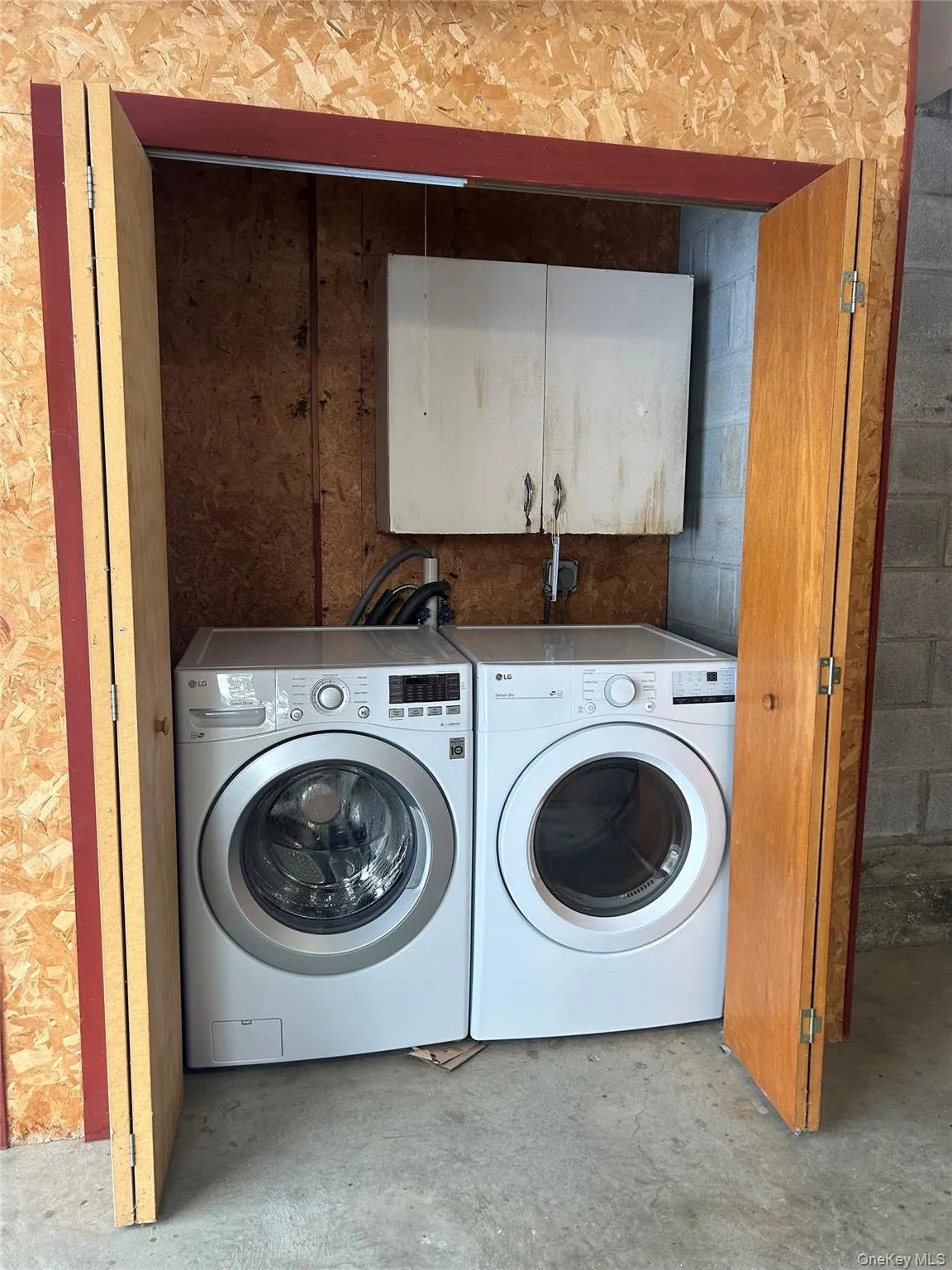 Washroom featuring washing machine and clothes dryer, unfinished concrete floors, and cabinet space Washroom featuring washing machine and clothes dryer, unfinished concrete floors, and cabinet space
