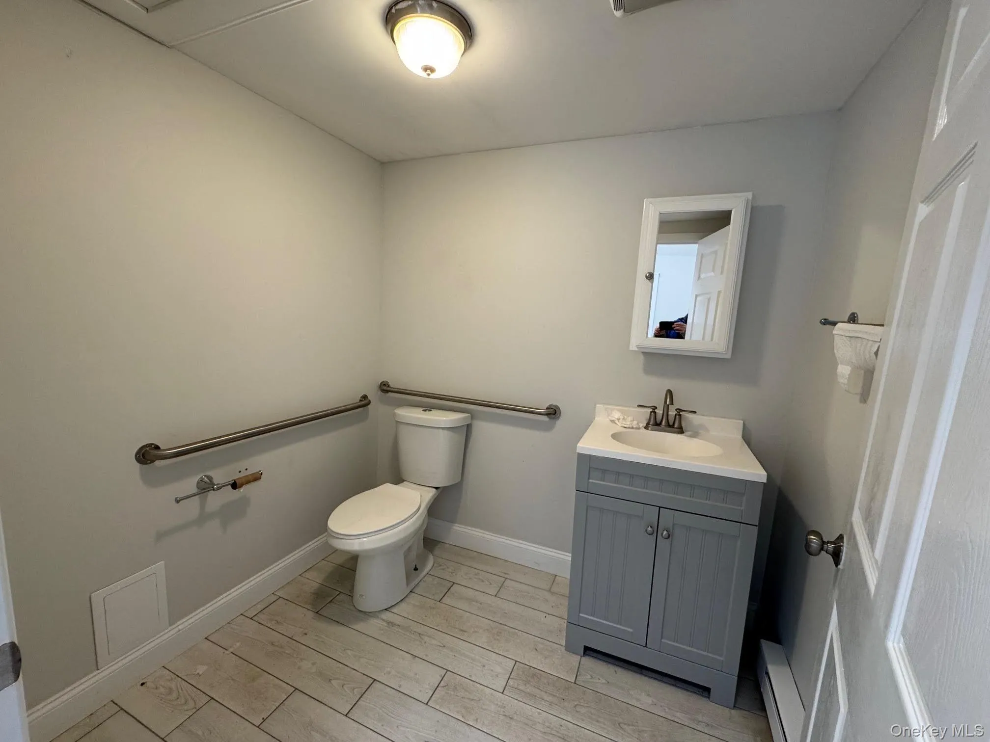 Washroom with vanity, wood tiled floors, and a baseboard radiator Washroom with vanity, wood tiled floors, and a baseboard radiator