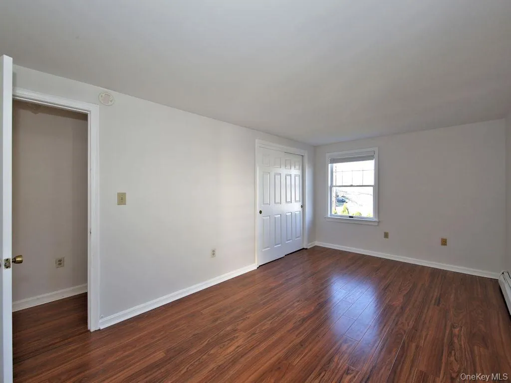 Unfurnished room with baseboards and dark wood-style flooring Unfurnished room with baseboards and dark wood-style flooring