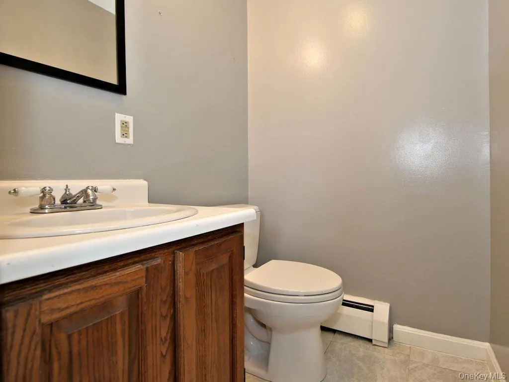 Half bath with vanity, a baseboard heating unit, and light tile patterned floors Half bath with vanity, a baseboard heating unit, and light tile patterned floors