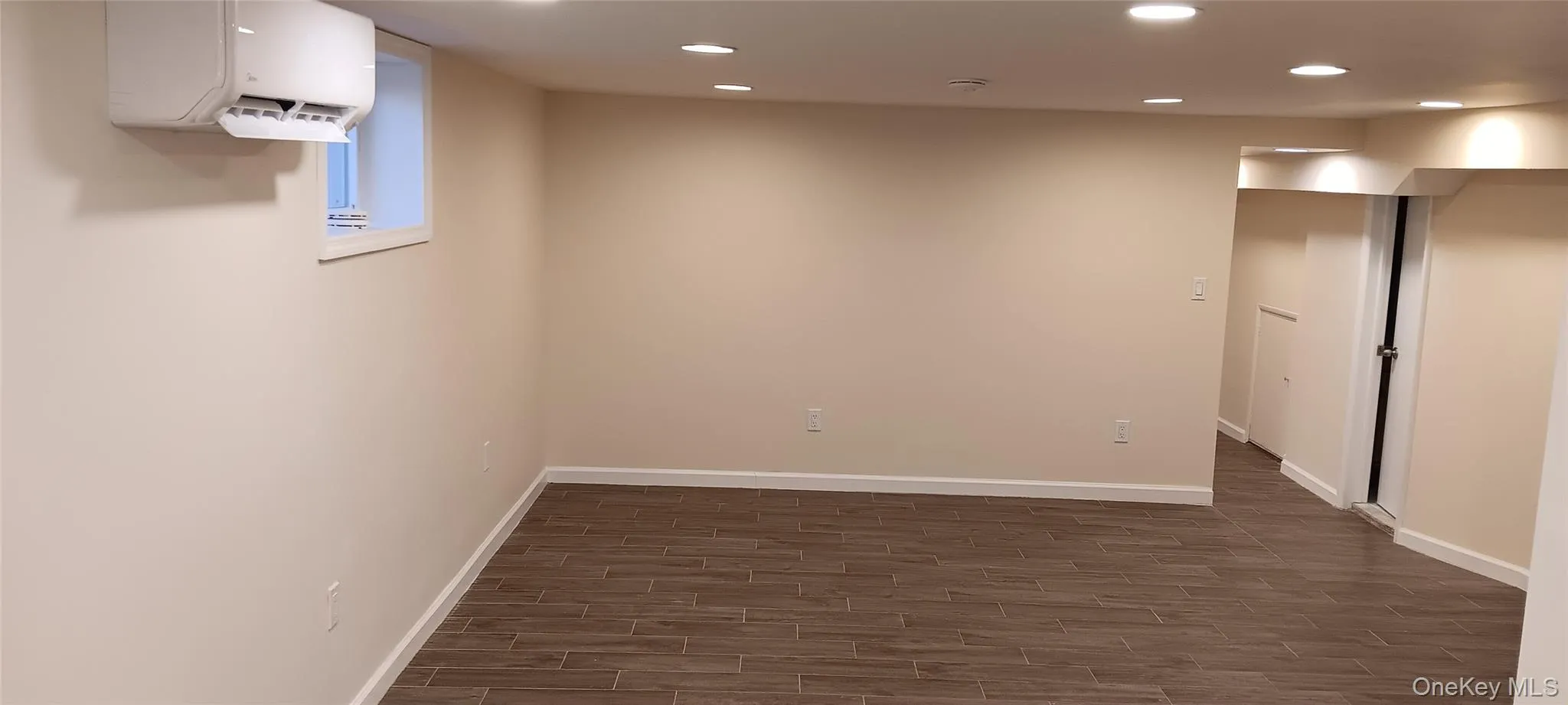 Below grade area with a wall mounted air conditioner, recessed lighting, and wood tiled floors Below grade area with a wall mounted air conditioner, recessed lighting, and wood tiled floors