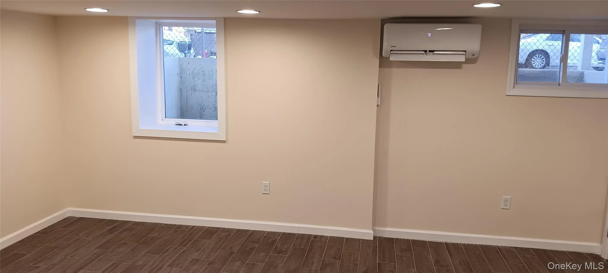Below grade area featuring wood finish floors, a wall unit AC, and recessed lighting Below grade area featuring wood finish floors, a wall unit AC, and recessed lighting